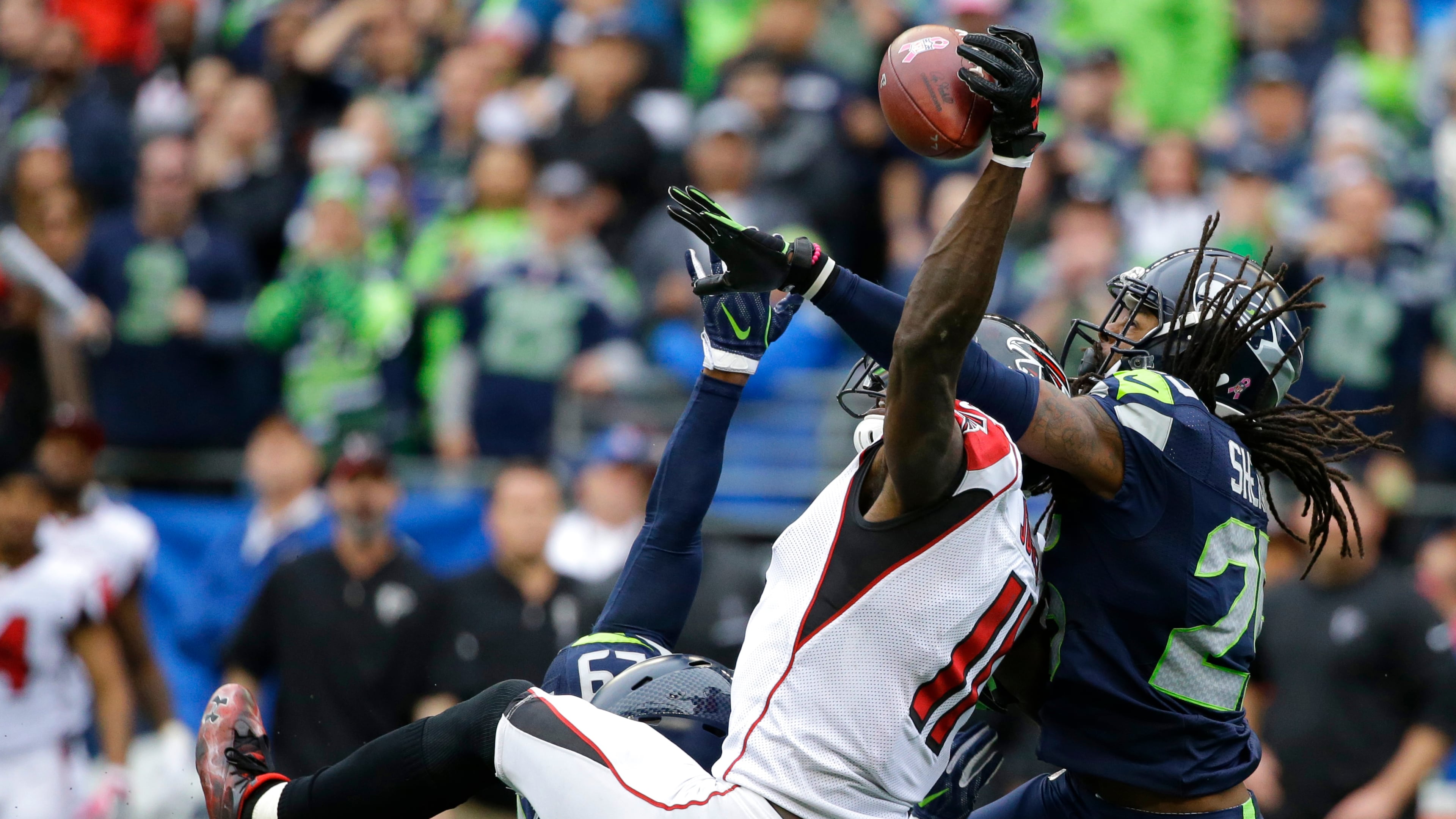 Seattle Seahawks cornerback Richard Sherman, right, and Earl Thomas (obscured) break up a pass intended for Falcons wide receiver Julio Jones (11) on Sunday, Oct. 16, 2016, in Seattle. The Seahawks beat the Falcons 26-24. (AP Photo/Elaine Thompson)