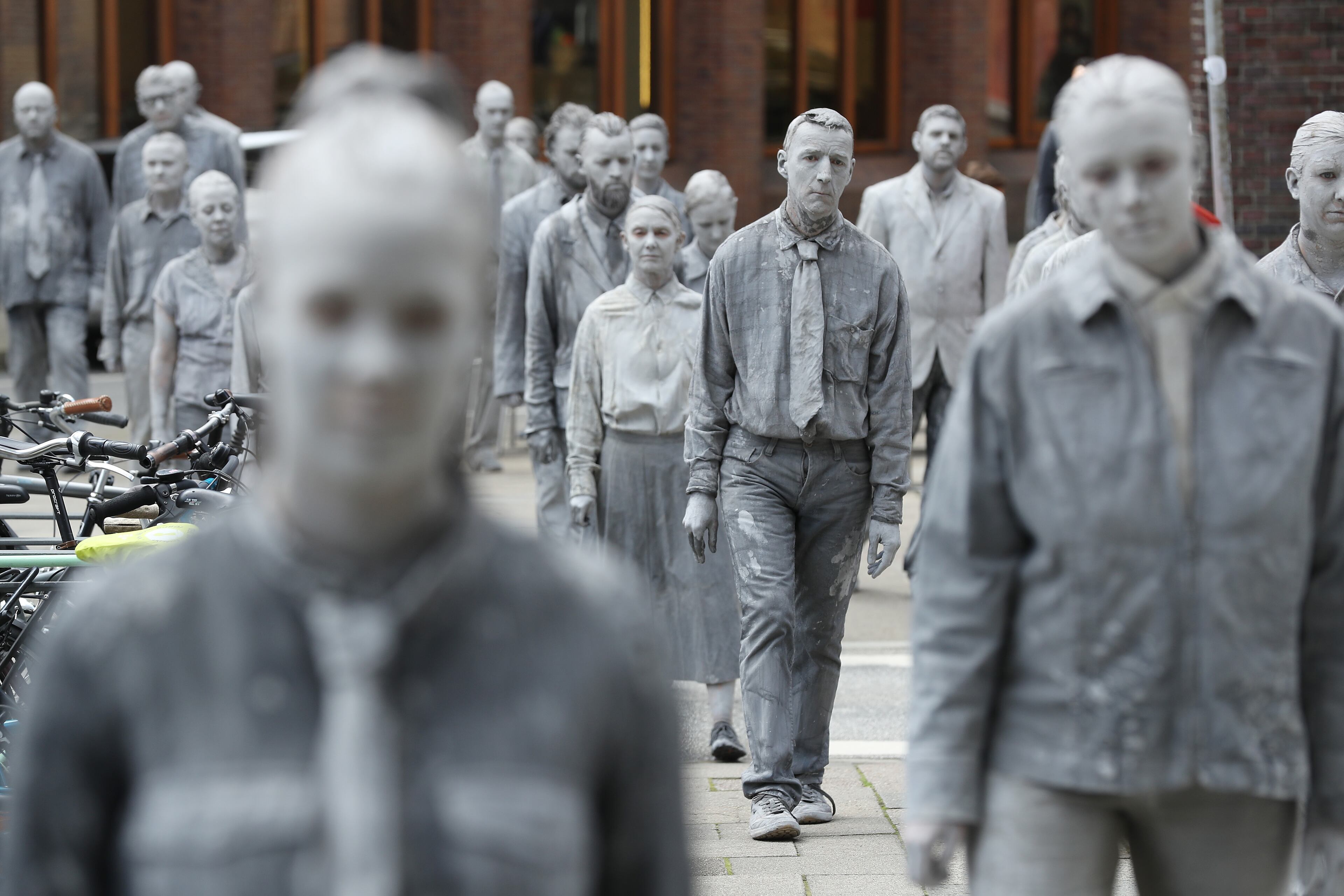 HAMBURG, GERMANY - JULY 05: Performance artists covered in clay to look like zombies walk trance-like through the city center during a preliminary performance on July 5, 2017 in Hamburg, Germany. In a two-hour show hundreds of actors took part in a creative public appeal for more humanity and self-responsibility ahead of the upcoming G20 summit. The G20 economic summit takes place in Hamburg July 7-8. (Photo by Sean Gallup/Getty Images)