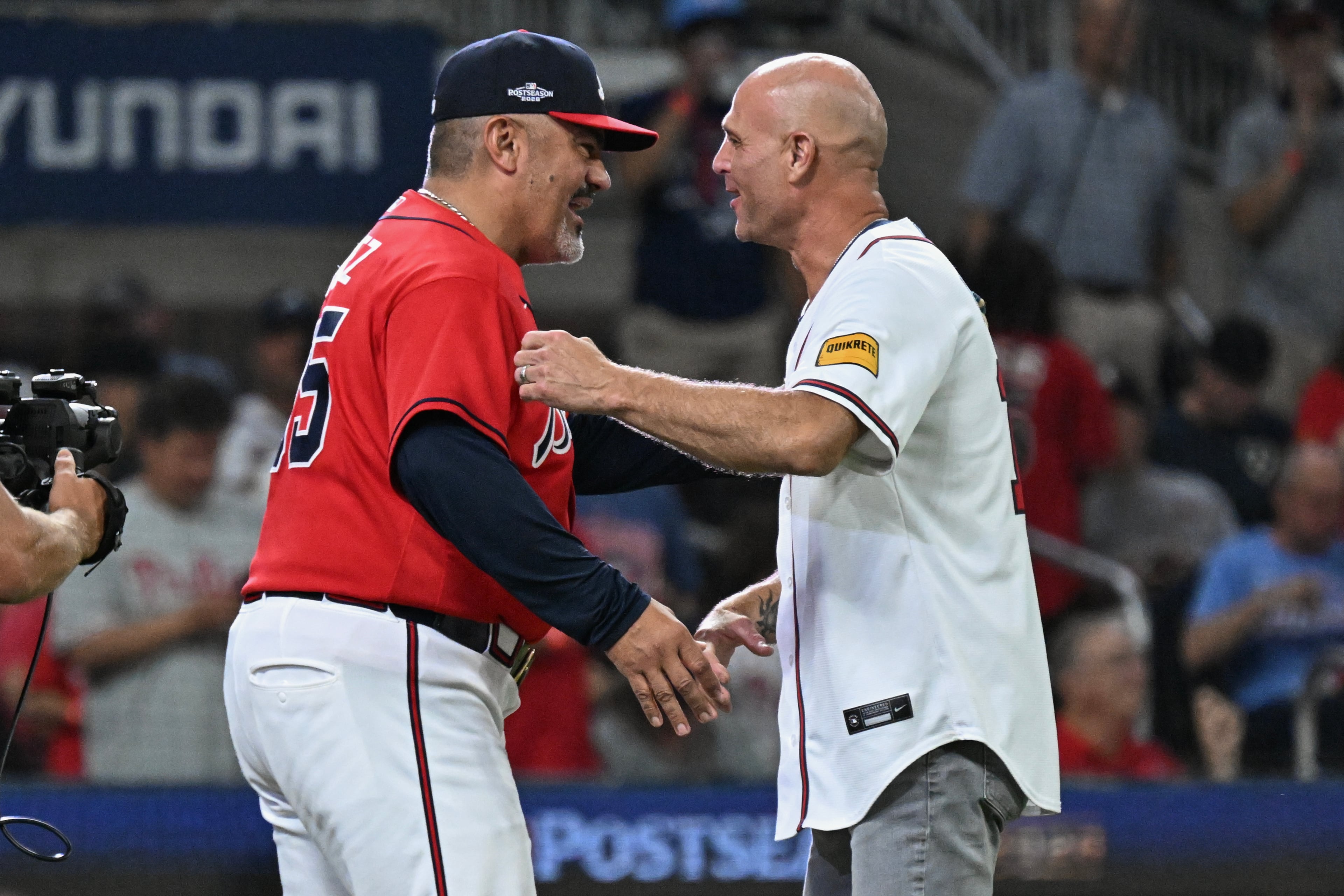 Former Atlanta Braves pitcher Tim Hudson, right, greets Atlanta Braves major league coach Eddie Prez (95) after throwing out the ceremonial first pitch before Game 3 of a MLB National League Wild Card playoff series between the Atlanta Braves and the Philadelphia Phillies, Thursday, Oct. 1, 2026, in Atlanta. (Hyosub Shin/AJC)