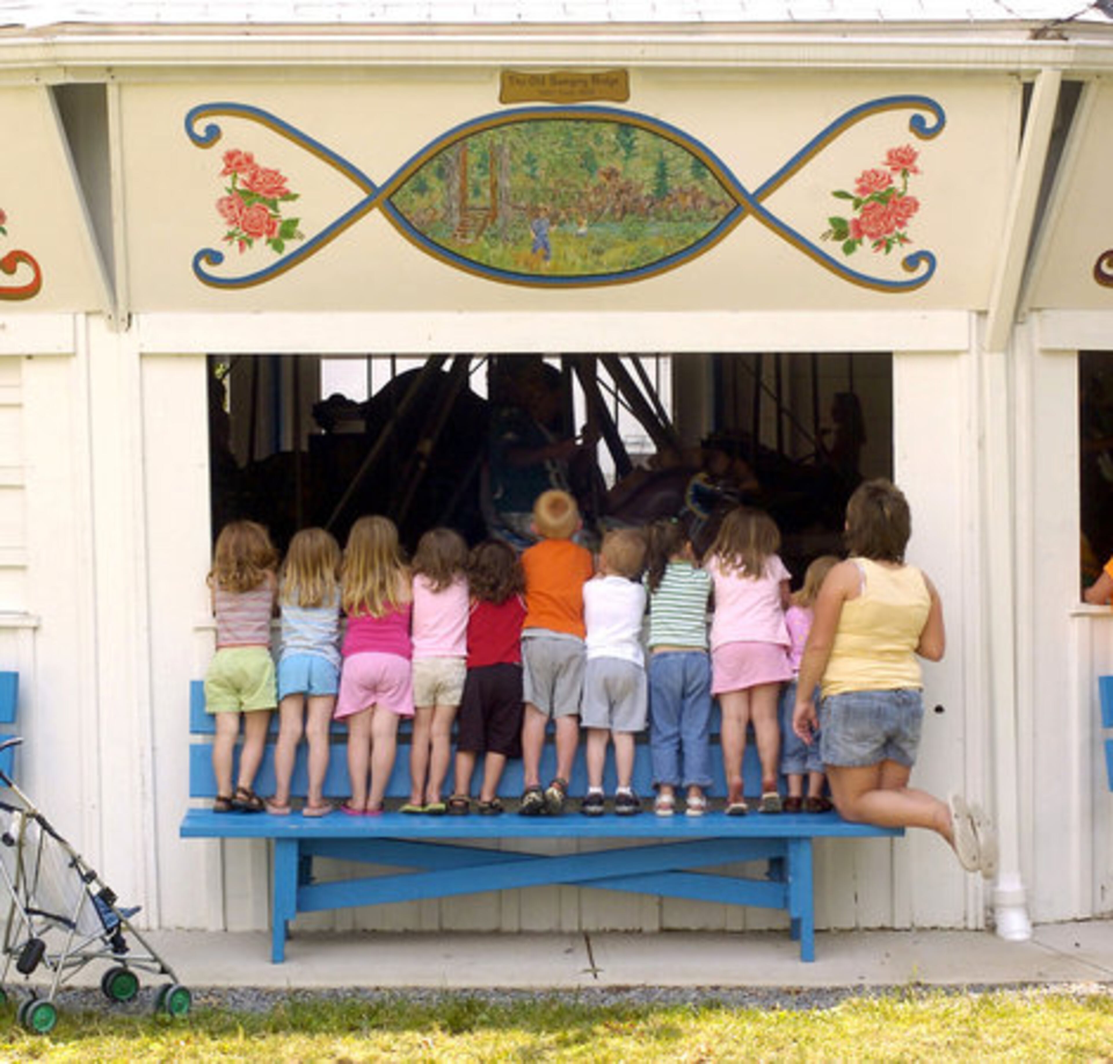 On Wednesday in Millville, Pa., children from the Eieio Play & Care Center stand on a bench outside of a merry-go-round to watch their playmates on the community park's ride.