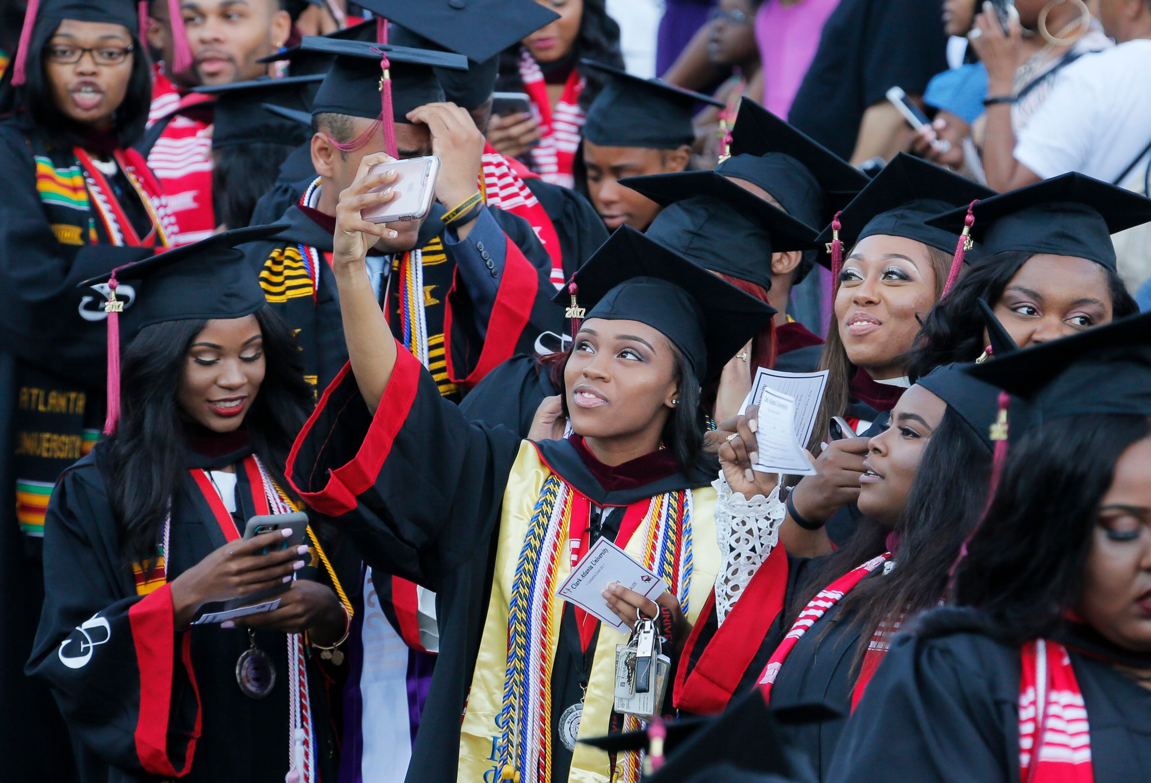 5/22/17 - Atlanta - Some graduates look toward the stands and family members, while others are on their phones as they enter during the Processional. Clark Atlanta University's Panther Stadium was the site of their 28th annual Commencement. Businessman William Pickard gave the commencement address. Rev. Jesse Jackson, who received an honorary degree, also spoke. Panther Stadium, BOB ANDRES /BANDRES@AJC.COM