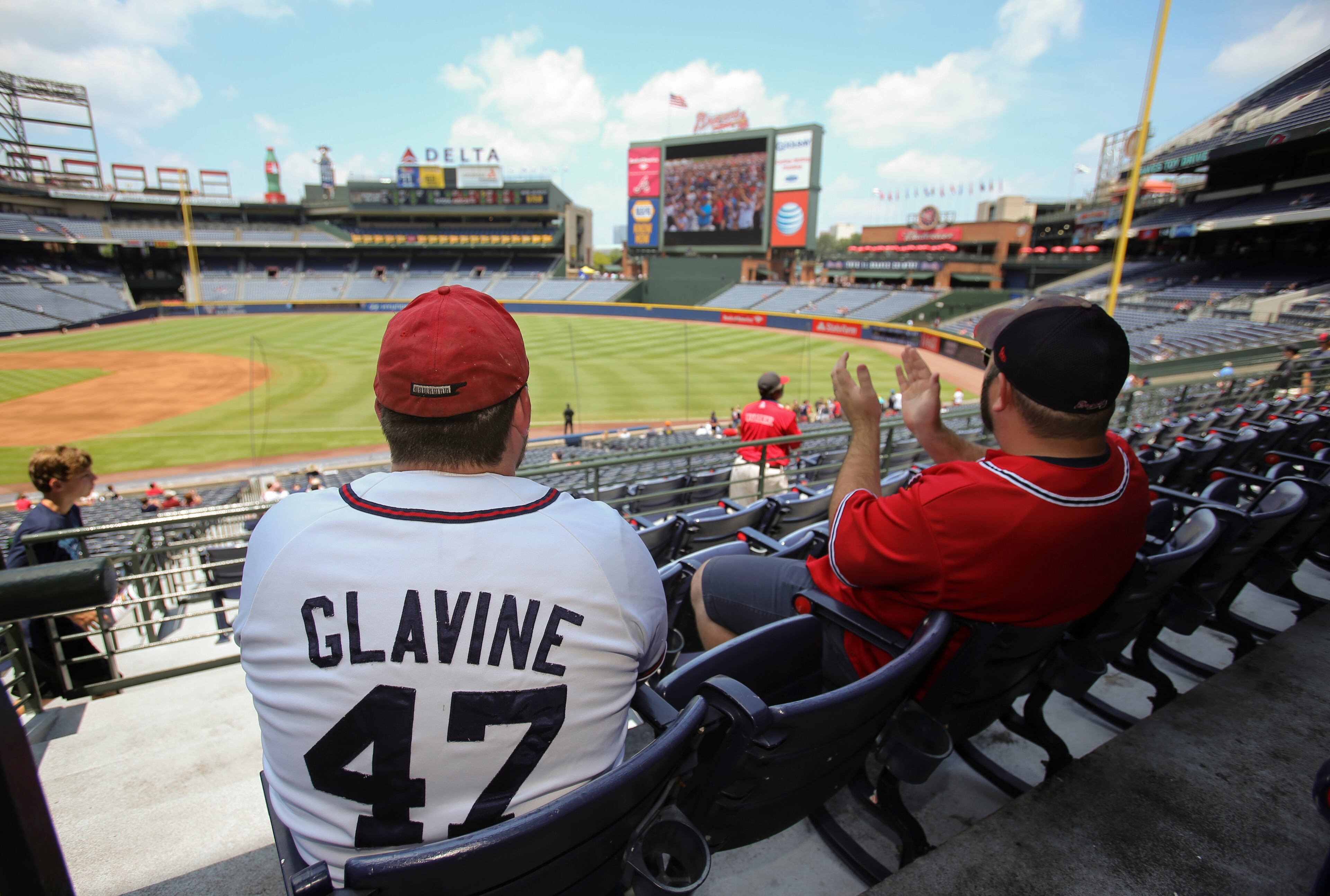 Wearing a Tom Glavine jersey, Atlanta Braves fan Stephen Cunningham, of Waynesboro, left, and Jonagh Benasuly, of Atlanta, watch the 2014 National Baseball Hall of Fame induction ceremony before the start of the Braves game against the San Diego Padres at Turner Field Sunday afternoon in Atlanta, Ga., July 27, 2014. Three former Braves -- manager Bobby Cox and pitchers Greg Maddux and Tom Glavine -- were inducted into the Baseball Hall of Fame Sunday afternoon. JASON GETZ / SPECIAL