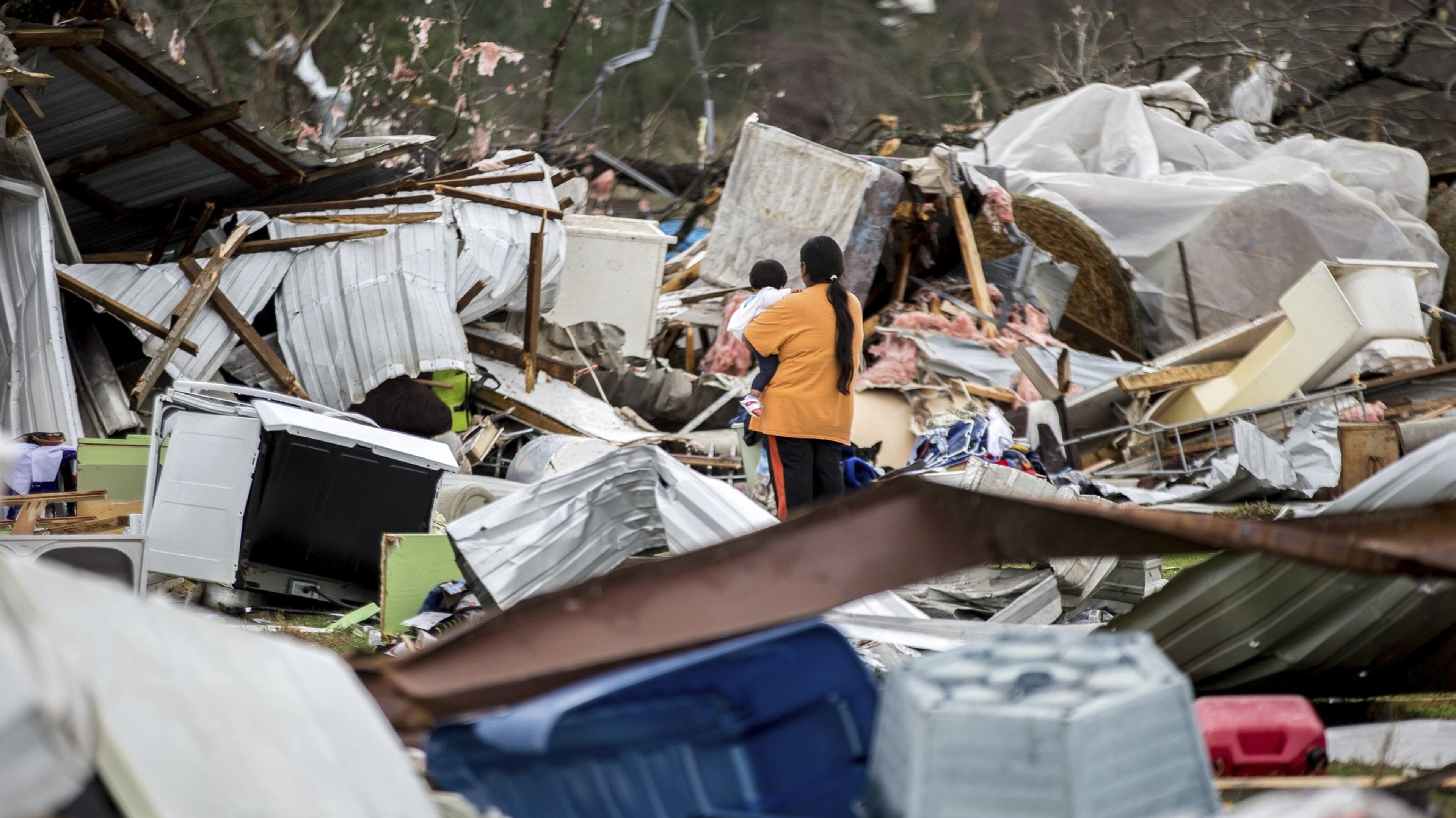 A woman holds a child while walking amid tornado damage in Adel, Ga. (AP Photo/Branden Camp)