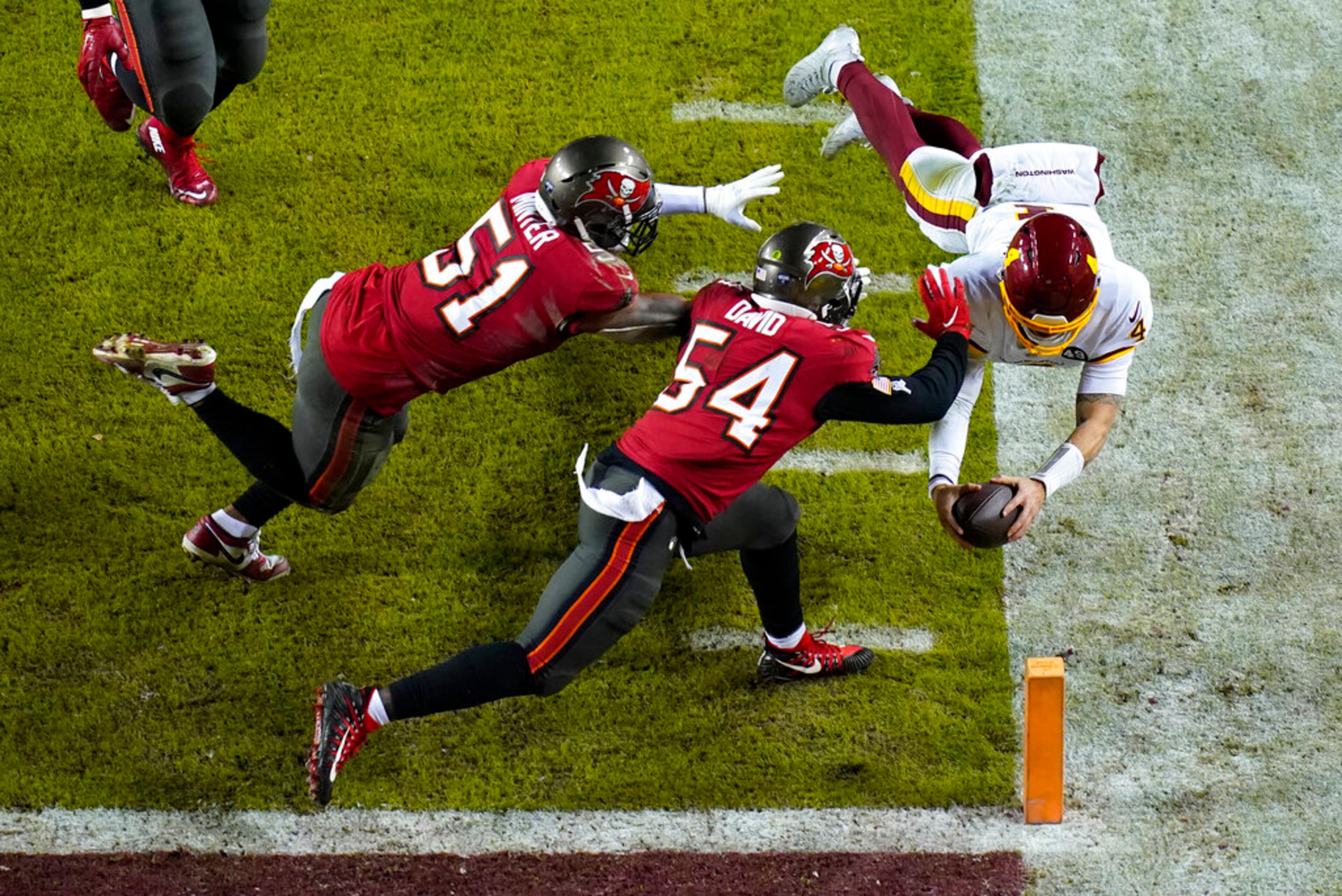 Washington Football Team quarterback Taylor Heinicke (4) dives toward the end zone to score a touchdown against Tampa Bay Buccaneers inside linebackers Kevin Minter (51) and Lavonte David (54) during the second half of an NFL wild-card playoff football game, Saturday, Jan. 9, 2021, in Landover, Md. (AP Photo/Al Drago)