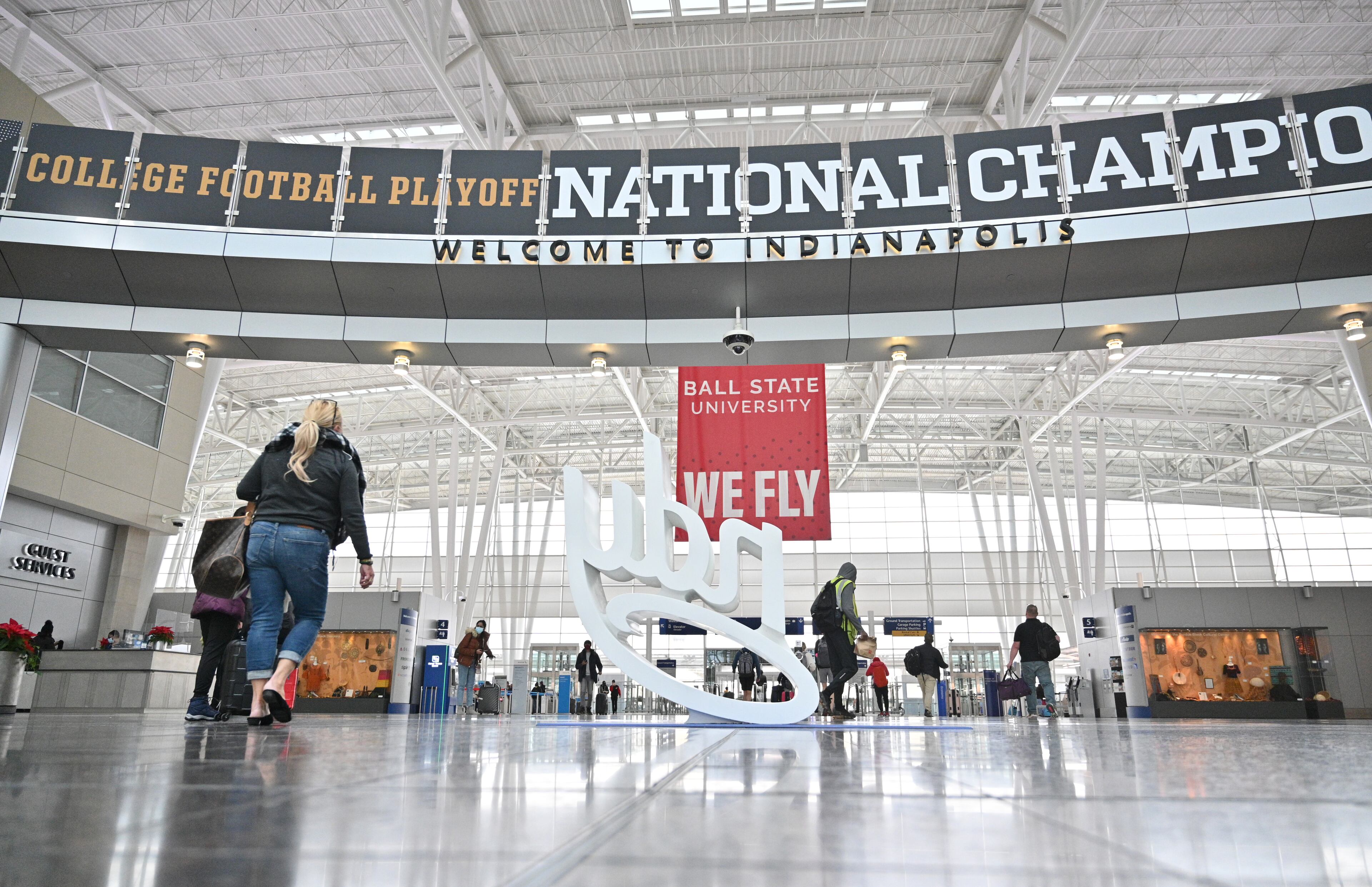 January 6, 2022 Indianapolis, IN - Airport travelers pass by National Championship displays at Indianapolis International Airport on Thursday, January 6, 2022. Downtown Indianapolis set to host the 2022 College Football Playoff National Championship game between Georgia and Alabama. (Hyosub Shin / Hyosub.Shin@ajc.com)