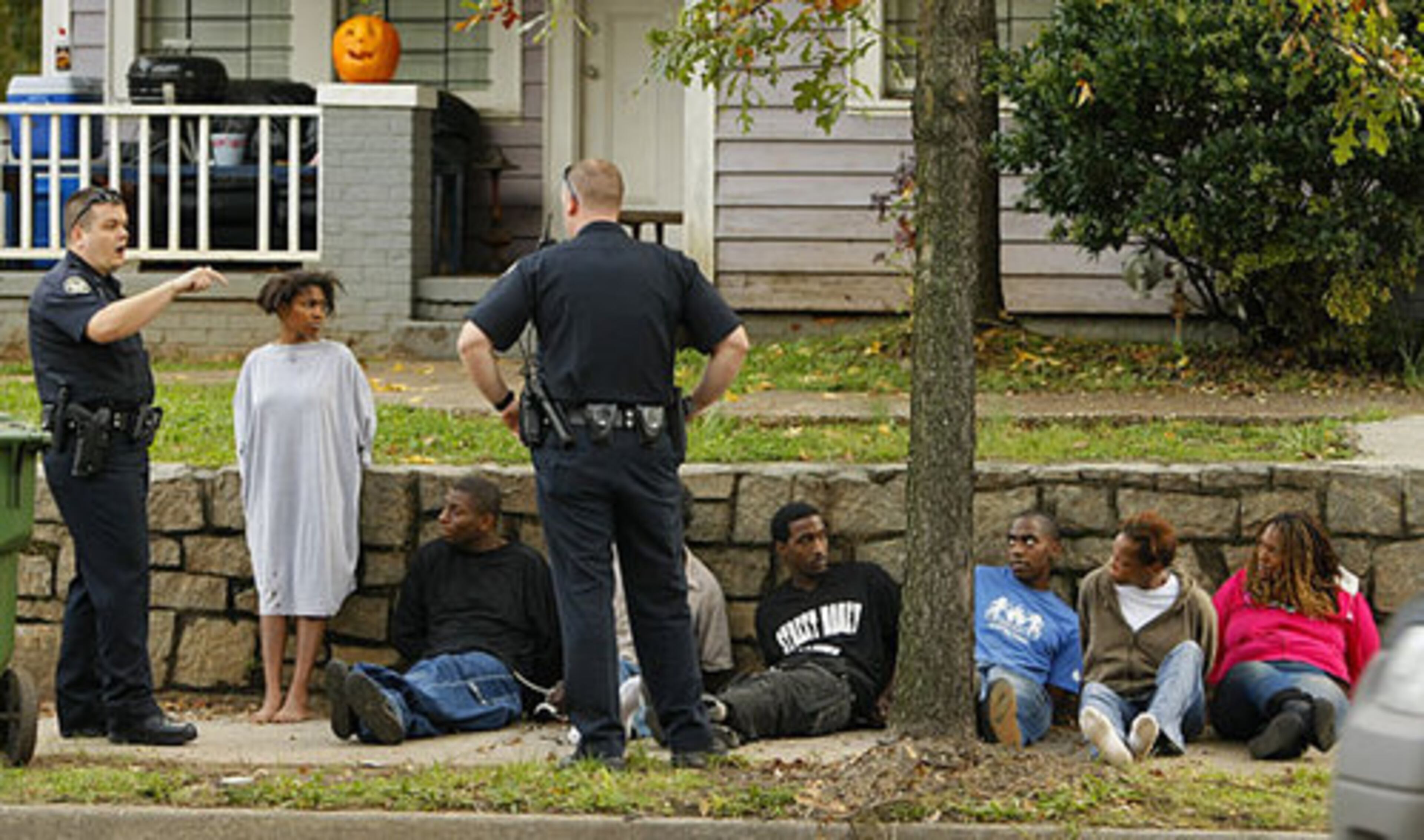 Police watch over suspects while waiting for transport.