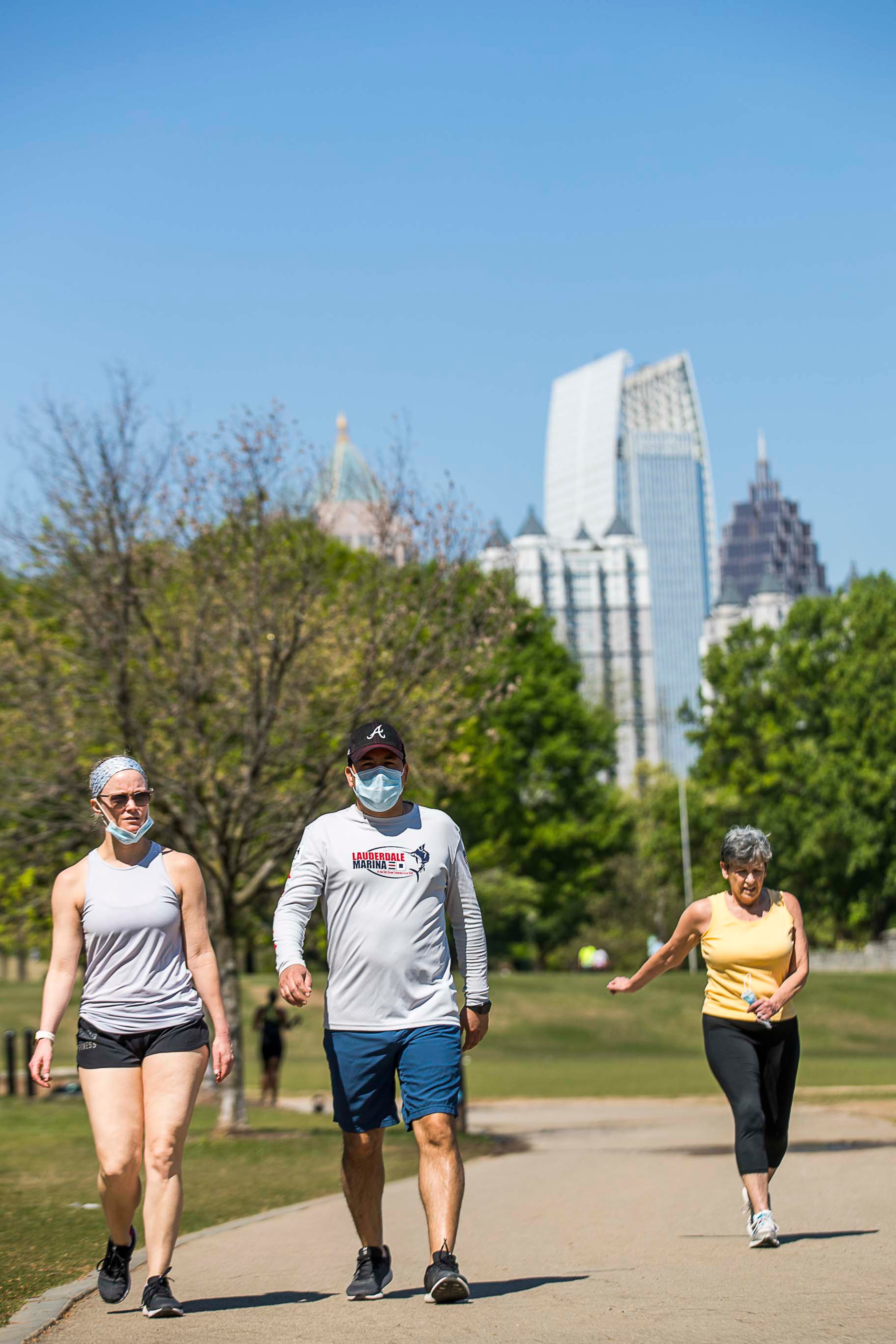 04/06/2020 - Atlanta, Georgia - Couple Paula Chesser (left) and Dr. Jose Lizcano (center) wear masks as they take a walk around Piedmont Park in Atlanta, Monday, April 6, 2020. Before the COVID-19 Pandemic, the couple planned to be in Europe this week for spring break. Instead, Dr. Lizcano, who works at Piedmont Atlanta Hospital, is taking a break at home with Chesser, a business teacher at North Atlanta High School. (ALYSSA POINTER / ALYSSA.POINTER@AJC.COM)