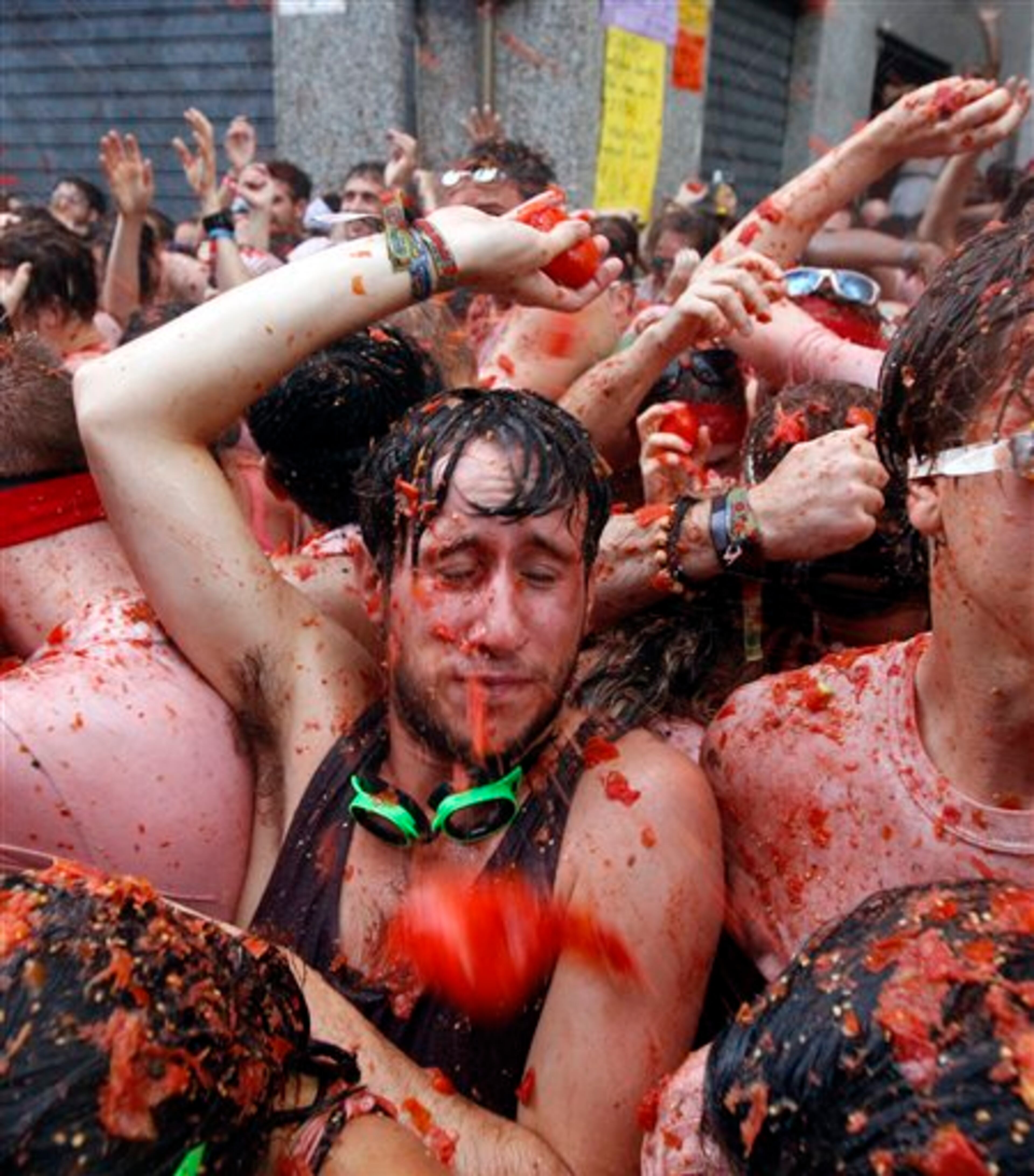 People throw tomatoes at each other during the annual "tomatina" tomato fight fiesta in the village of Bunol, 50 kilometers outside Valencia, Spain, Wednesday, Aug. 28, 2013. Thousands of people are splattering each other with tons of tomatoes in the annual "Tomatina" battle in recession-hit Spain, with the debt-burdened town charging participants entry fees this year for the first time. Bunol town says some 20,000 people are taking part in Wednesday's hour-long street bash, inspired by a food fight among kids back in 1945. Participants were this year charged some 10 euros ($13) to foot the cost of the festival. Residents do not pay. (AP Photo/Alberto Saiz)