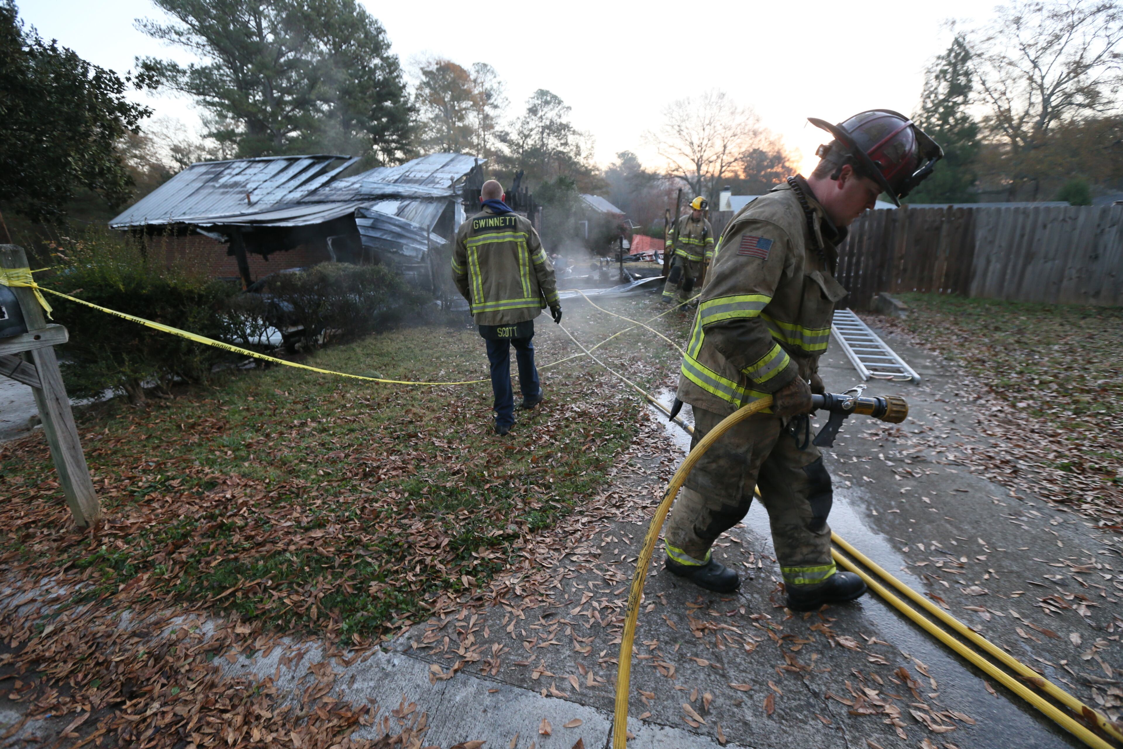 Gwinnett County fire fighters inspect the remains of a home after a fire late Sunday night in Lilburn. One person was found dead. When fire fighters arrived on scene, neighbors and police reported that an occupant was possibly still inside the burning home, Gwinnett County fire Capt. Tommy Rutledge said.