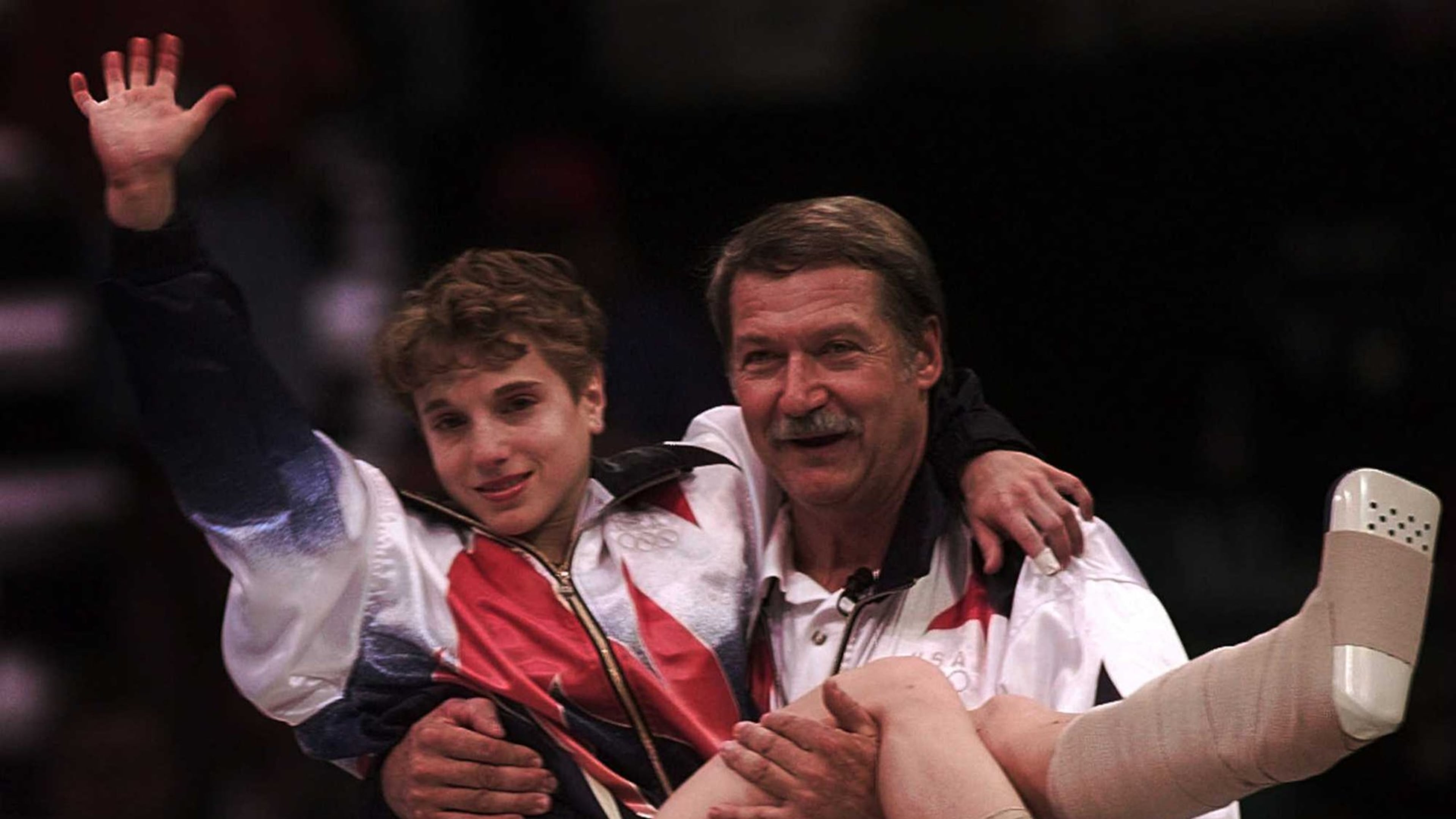 In an iconic image, U.S. gymnastics coach Bela Karolyi carries an injured Kerri Strug to the medal ceremony after her vault helped the American women win the team gold medal in the 1996 Olympics at the Georgia Dome. (AJC file photo)