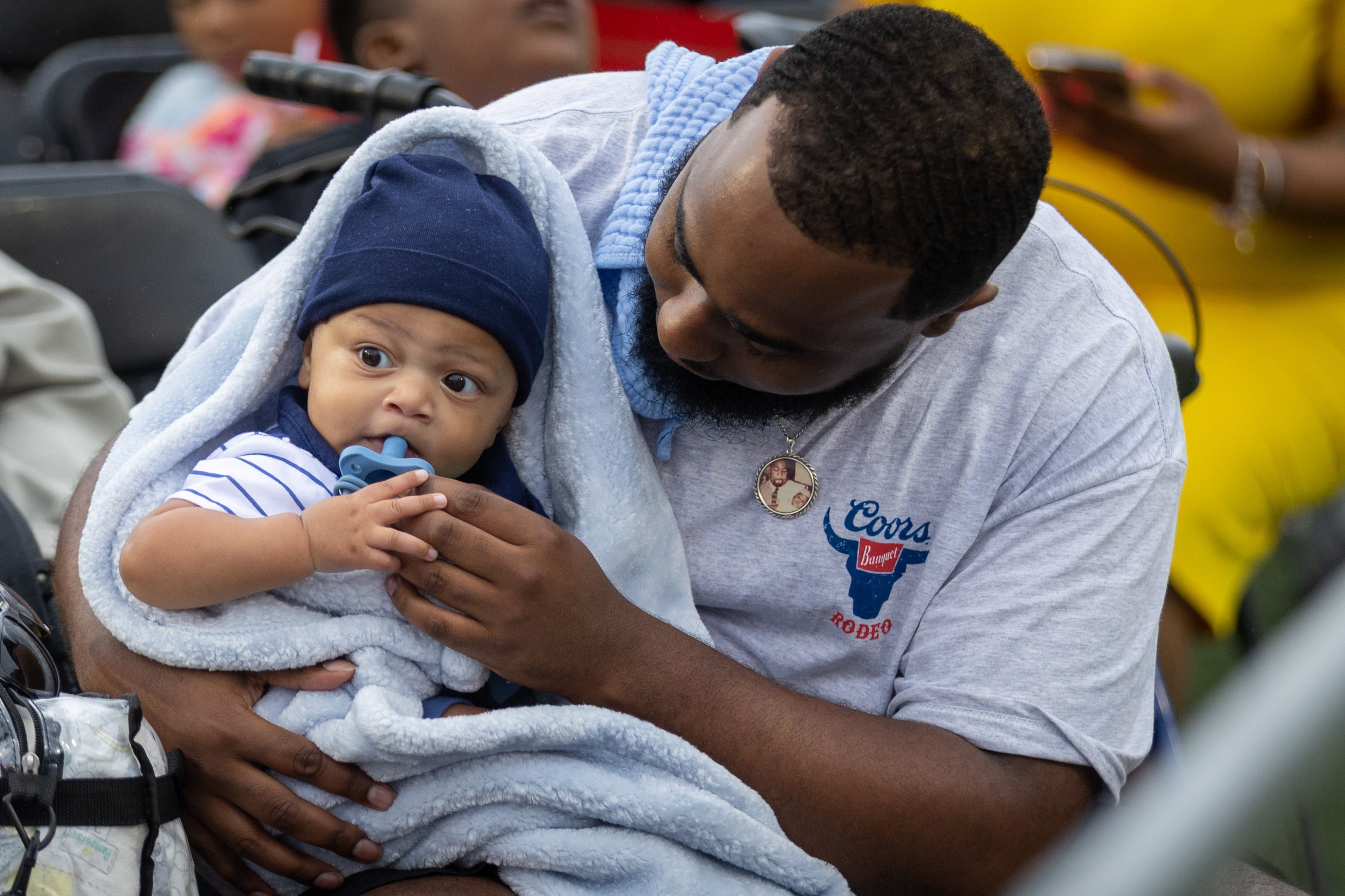 Kelan Carter tries to stay dry and warm with his son Markell while he waits for his wife, Chasty Starks, to graduate during Clark Atlanta University's commencement ceremony Saturday, May 20, 2023. (Steve Schaefer / steve.schaefer@ajc.com)