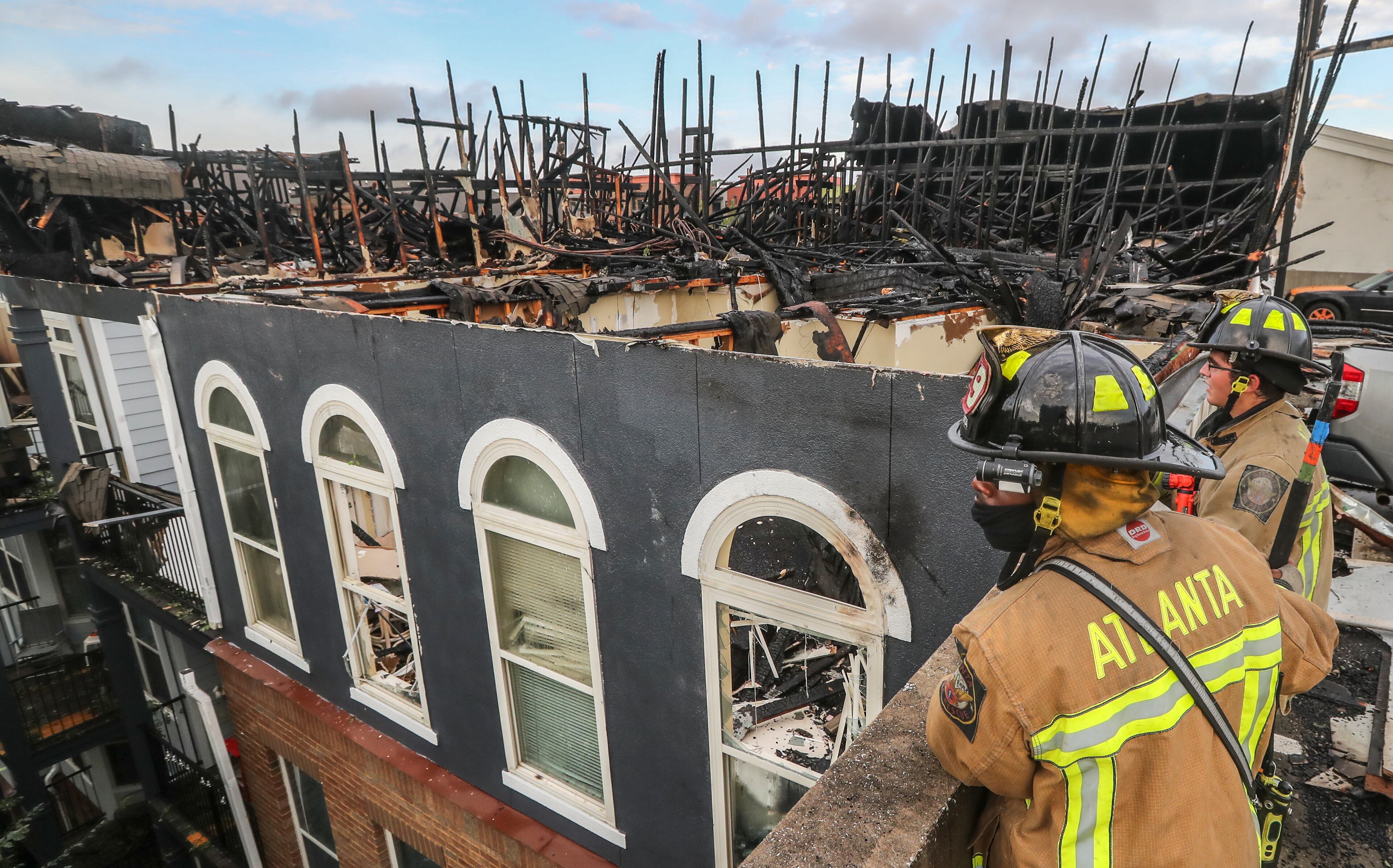 Atlanta firefighters on Thursday morning survey the damage after Wednesday's massive fire at the Avana on Main. JOHN SPINK/JSPINK@AJC.COM