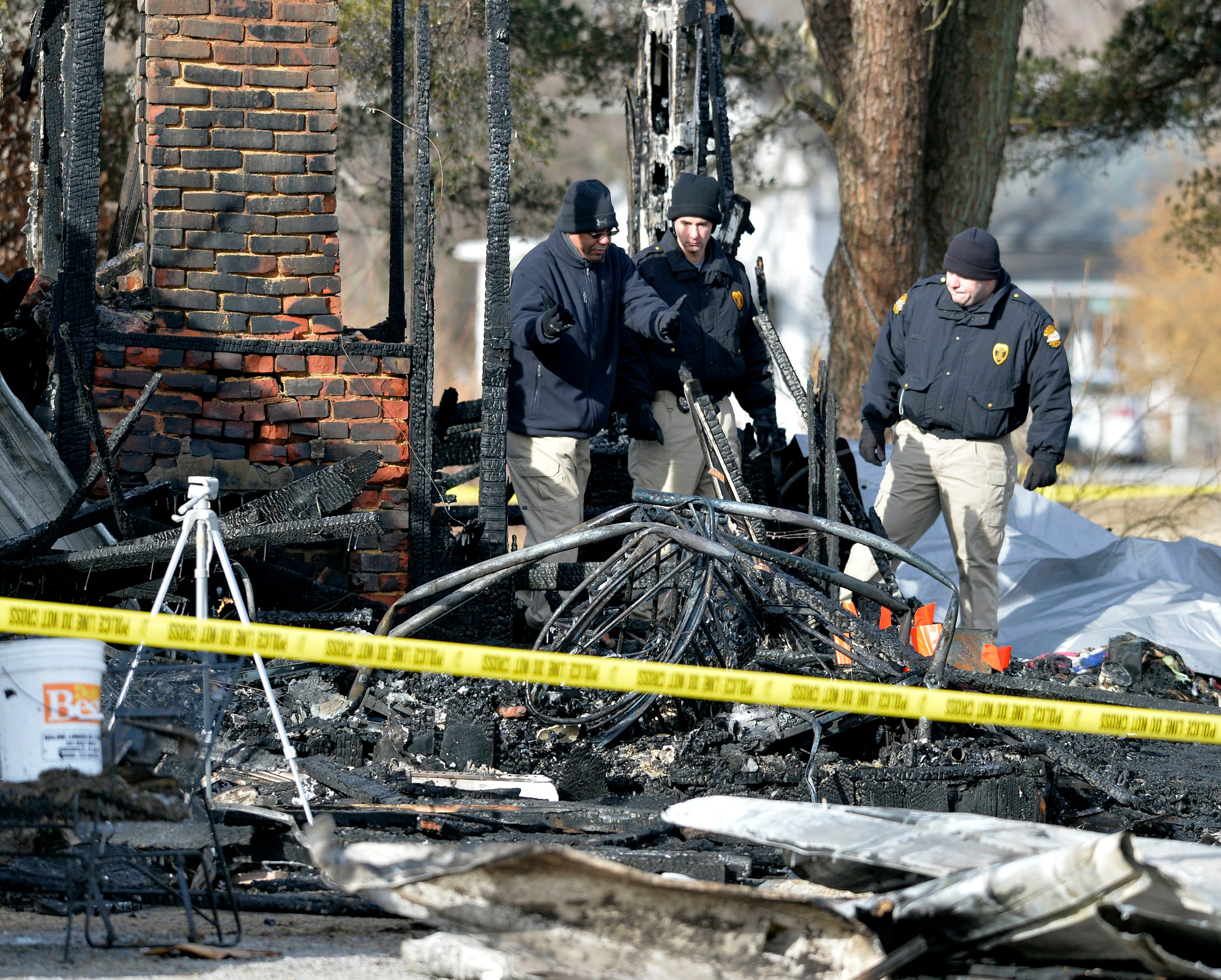 Kentucky State Fire investigators work at the scene of early morning house in Depoy, Ky. Thursday Jan. 30, 2014. As many as nine people were killed early Thursday in a house fire in rural western Kentucky and two people were taken to a hospital for treatment, officials said. Eleven people lived in the home in the Depoy community of Muhlenberg County, Greenville Assistant Fire Chief Roger Chandler said. (AP Photo/Timothy D. Easley)