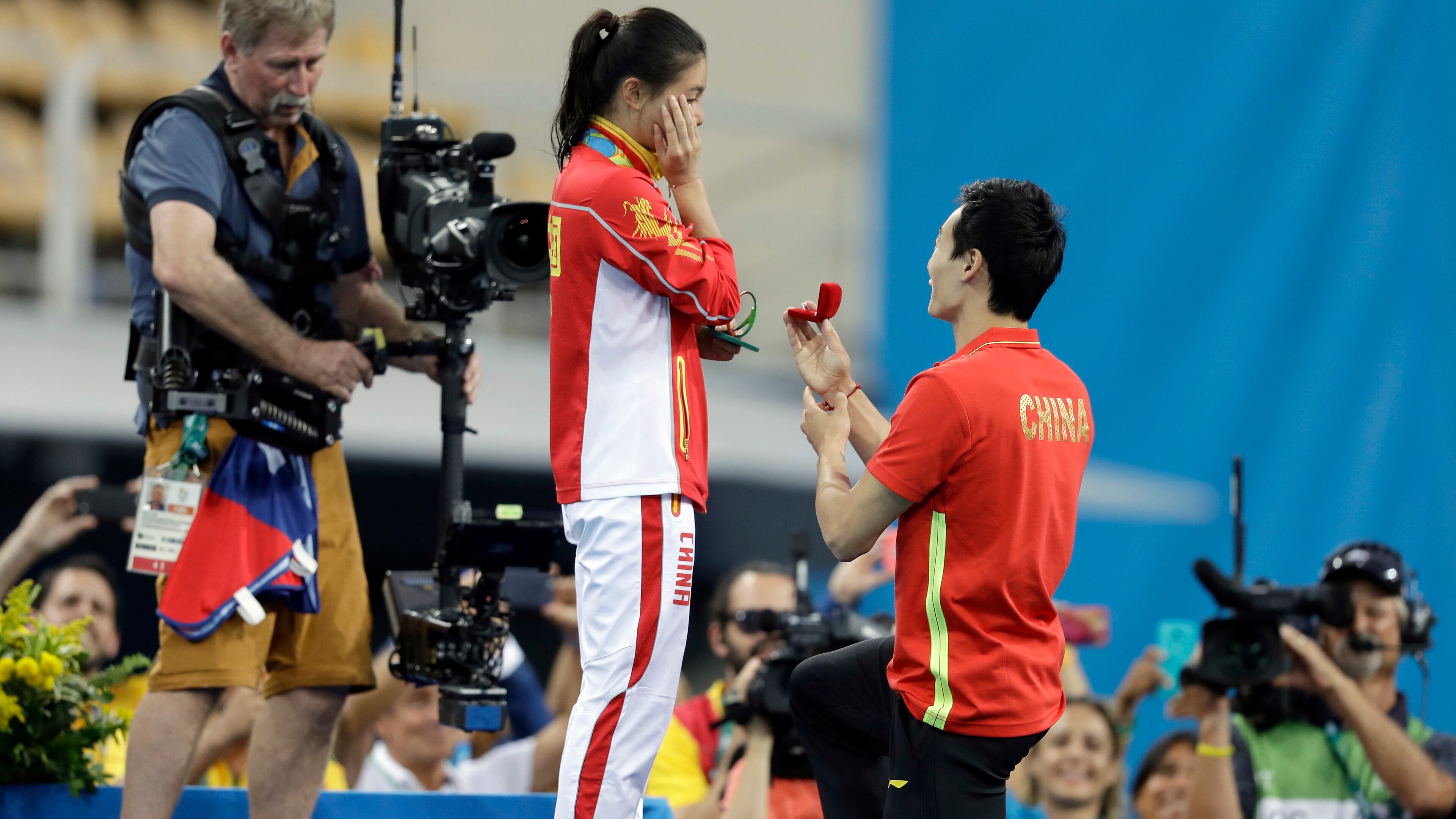 China's silver medalist He Zi, left, receivers a marriage proposal by China's diver Qin Ki, right, during the medal ceremony for the the women's 3-meter springboard diving final in the Maria Lenk Aquatic Center at the 2016 Summer Olympics in Rio de Janeiro, Brazil, Sunday, Aug. 14, 2016. (AP Photo/Michael Sohn)