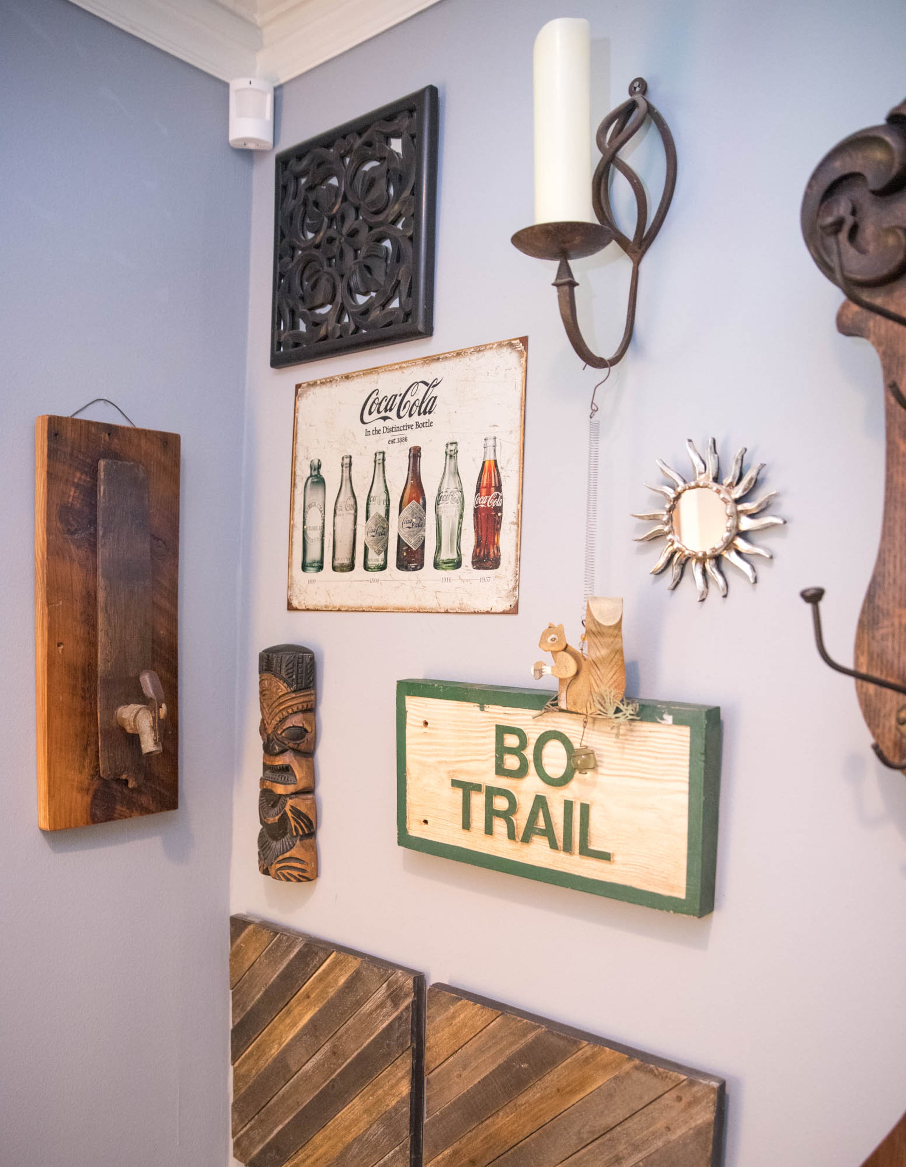 The "Bo Trail" sign on the gallery wall in Ben Ratossa and Adam Perry's living room is there in memory of one of their dogs, Bo, who passed away last year. The hanging squirrel just above the sign was a gift from a neighbor, and is placed right by Bo's sign, since watching the neighborhood squirrels was one of his favorite pastimes. Reynolds Rogers/For the AJC