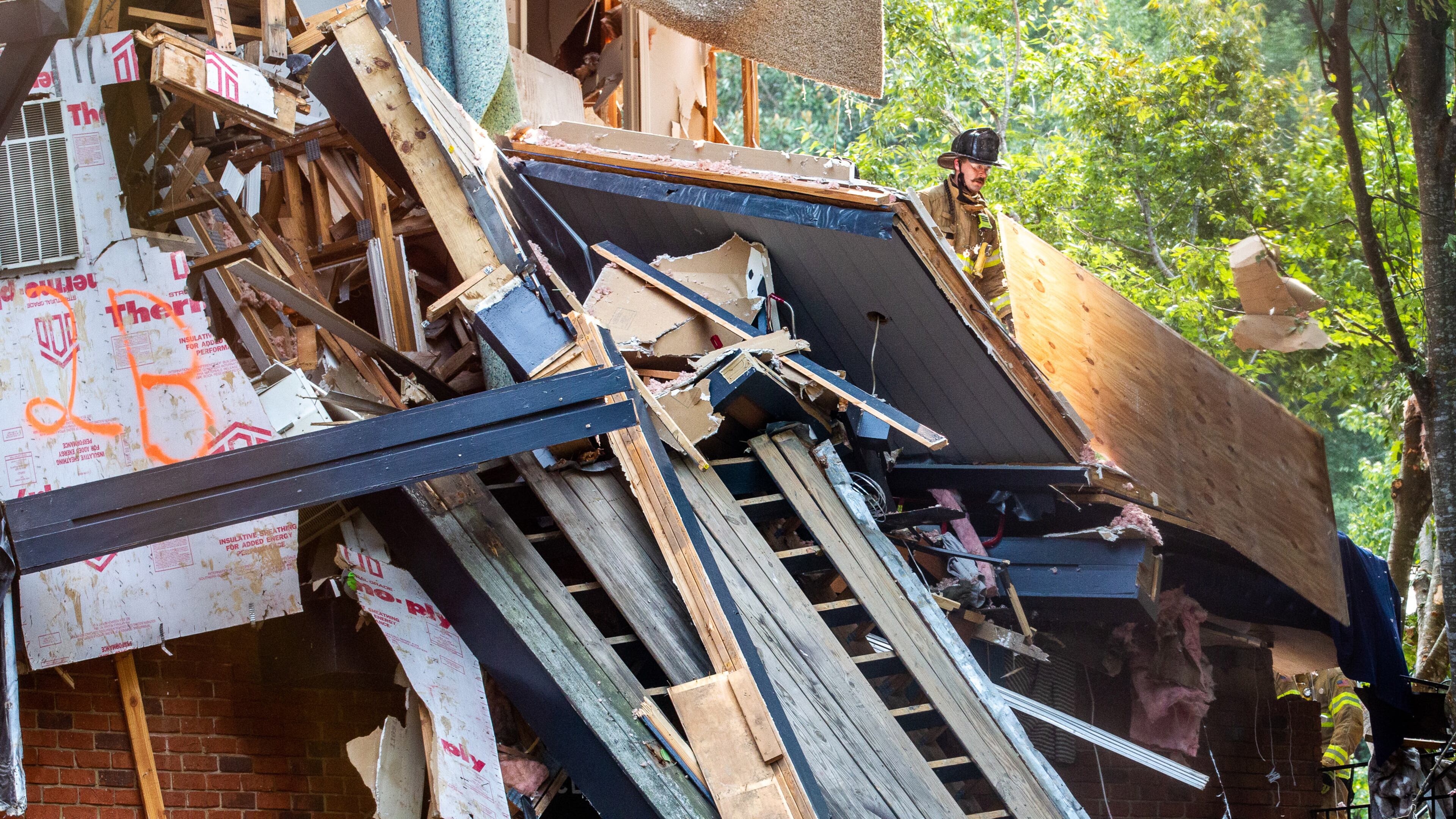 DeKalb County firefighters clear debris from the Arrive Perimeter apartment complex in Dunwoody after an explosion damaged the building Sunday afternoon.