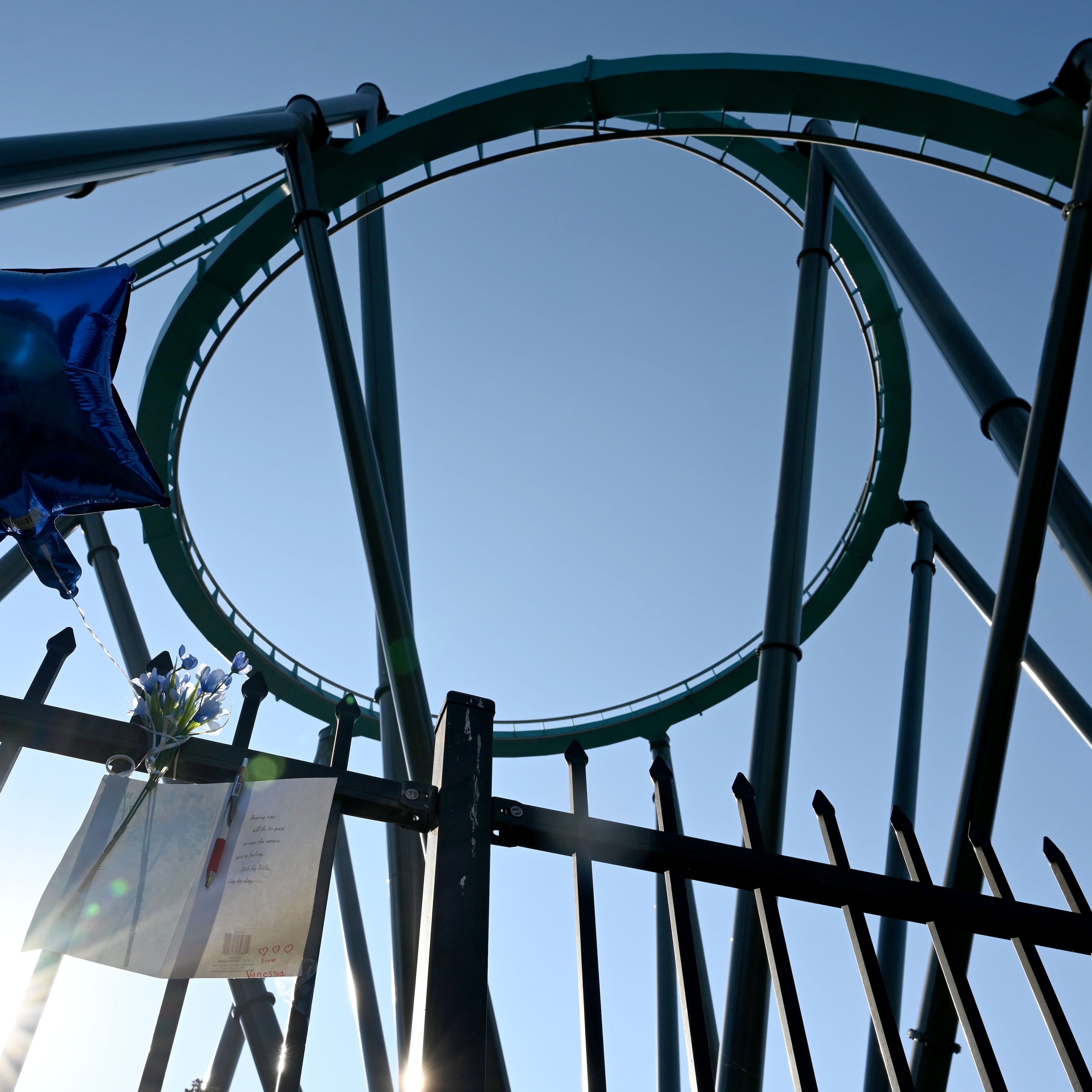 A memorial is displayed on the fence at Six Flags Over Georgia as the Goliath roller coaster is shown in the background on Thursday, Oct. 15, 2026. A 42-year-old Atlanta educator, Hassan Kariem, died after being ejected from the ride Oct. 12. (Hyosub Shin/AJC)