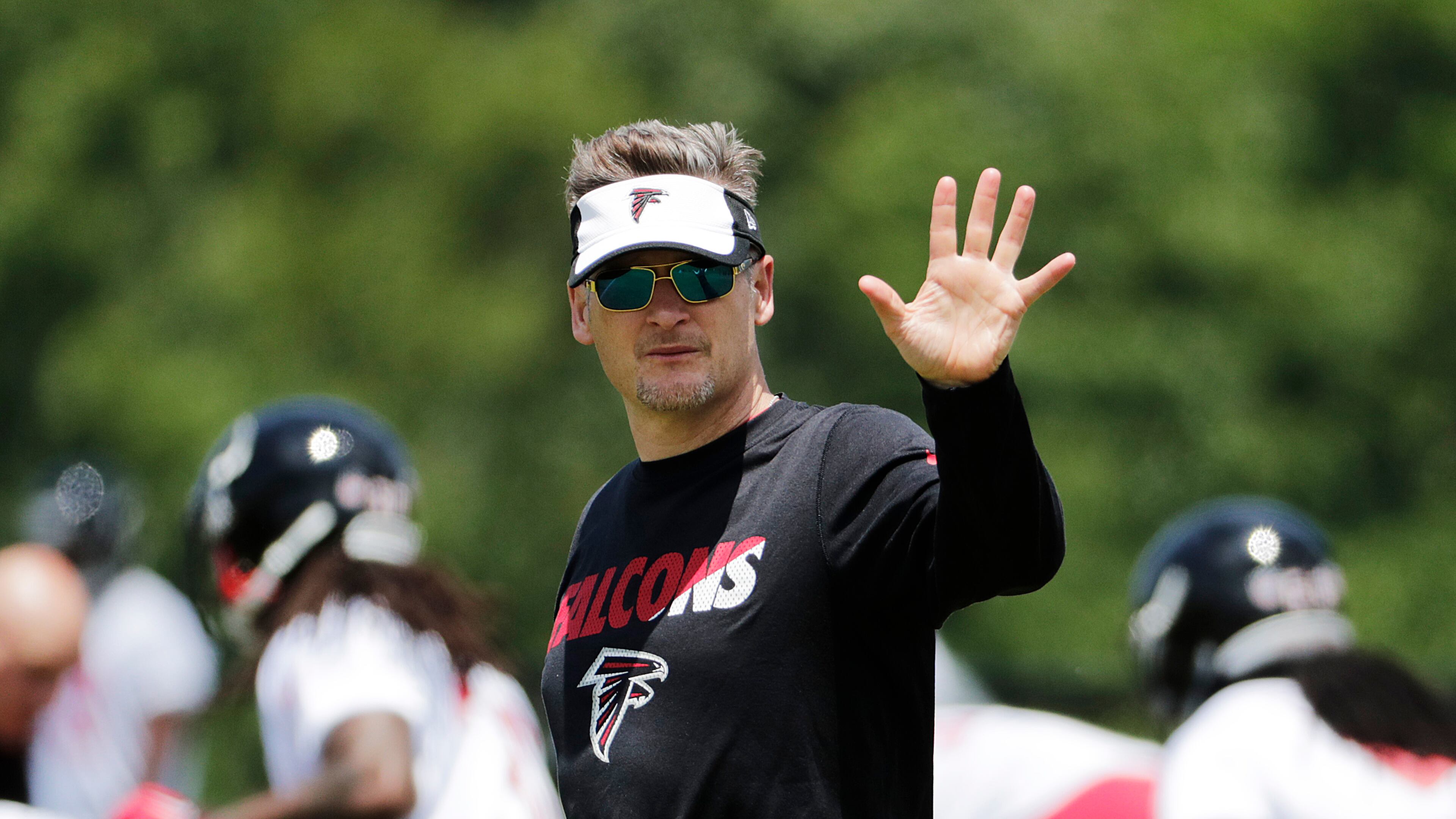 Atlanta Falcons general manager Thomas Dimitroff waves while walking across the field during a football practice Monday, May 23, 2016, in Flowery Branch. (AP Photo/David Goldman)