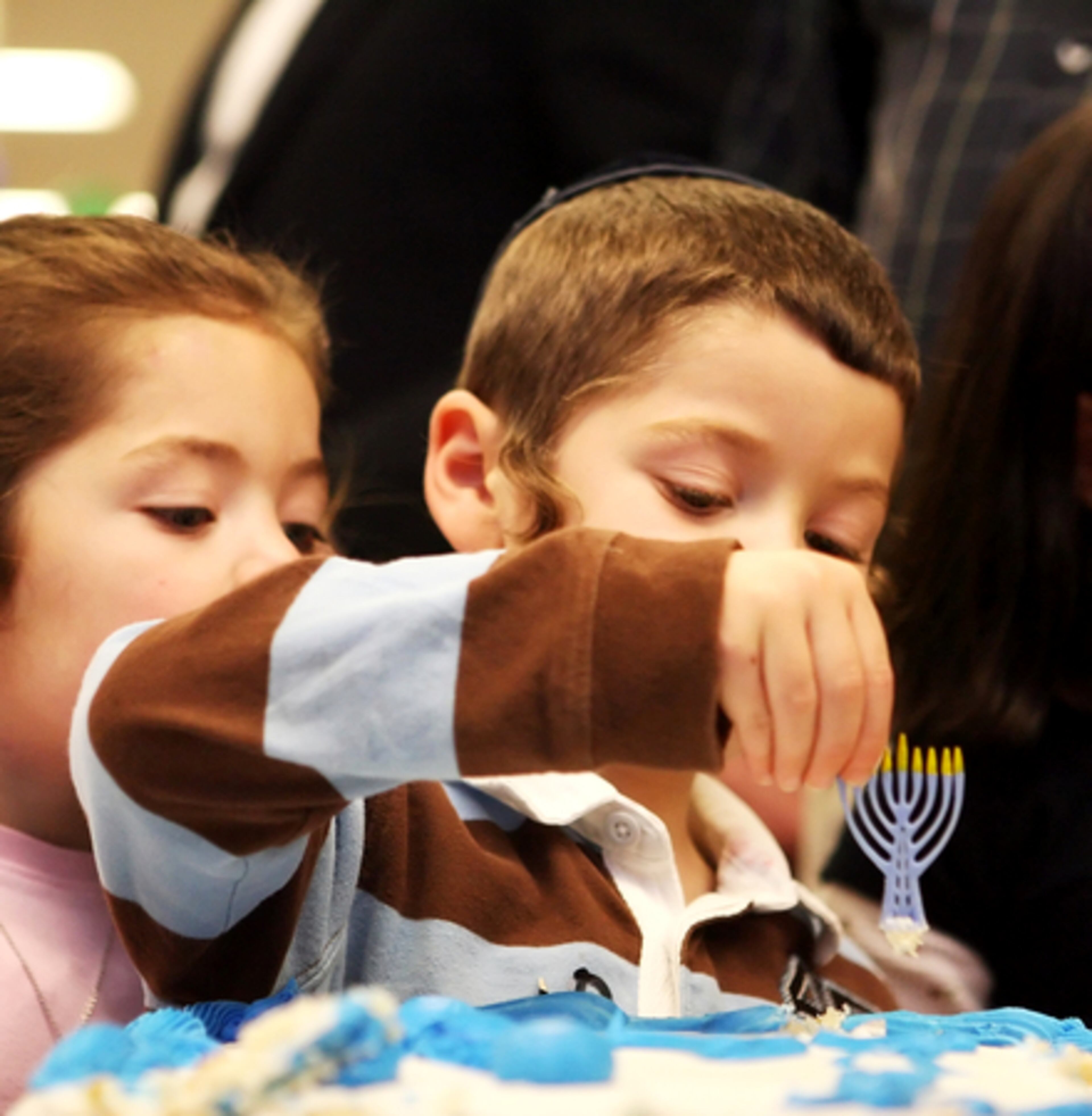 Shmuel Horowitz, son of Rabbi Horowitz, plucks an ornamental Menorah off the Hanukkah cake during the community celebration Sunday.