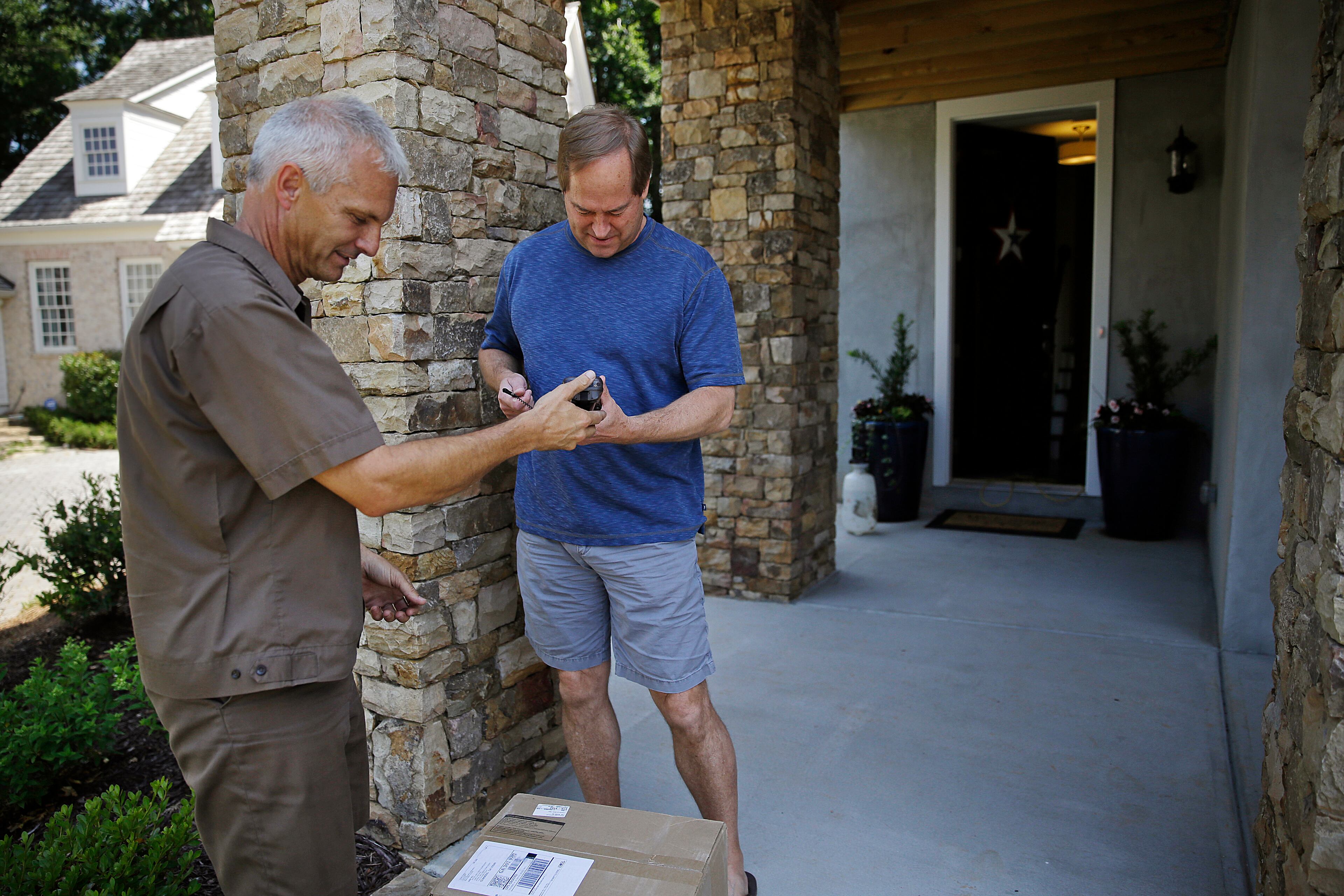 In this June 20, 2014 photo, United Parcel Service driver Marty Thompson, left, gets a signature from Peter Sundquist while making a delivery in Cumming, Ga. (AP Photo/David Goldman)