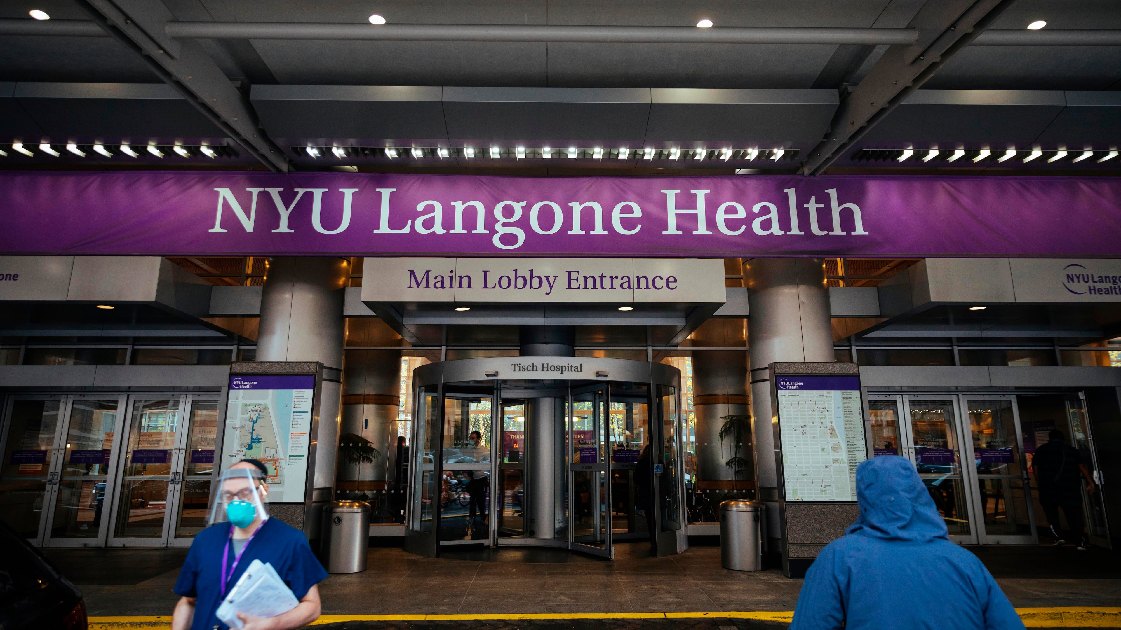 FILE - Health care workers walk in and out of the entrance at NYU-Langone Hospital on Dec. 14, 2020, in New York. (AP Photo/Kevin Hagen, File)