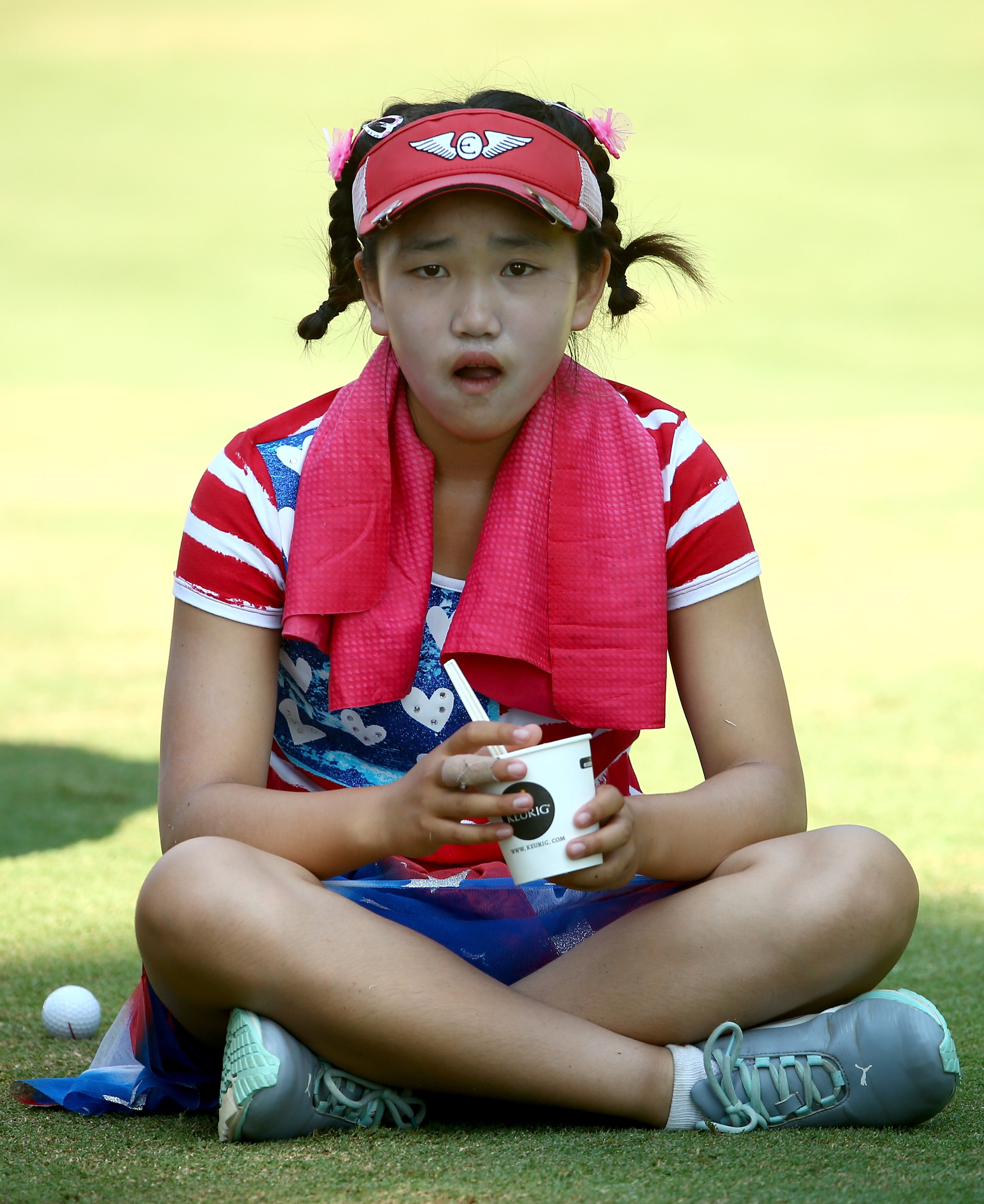 Eleven-year-old amateur Lucy Li of the United States takes a break as she waits to hit on the third hole during the first round of the 69th U.S. Women's Open at Pinehurst Resort & Country Club, Course No. 2 on June 19, 2014 in Pinehurst, North Carolina. (Photo by Streeter Lecka/Getty Images)