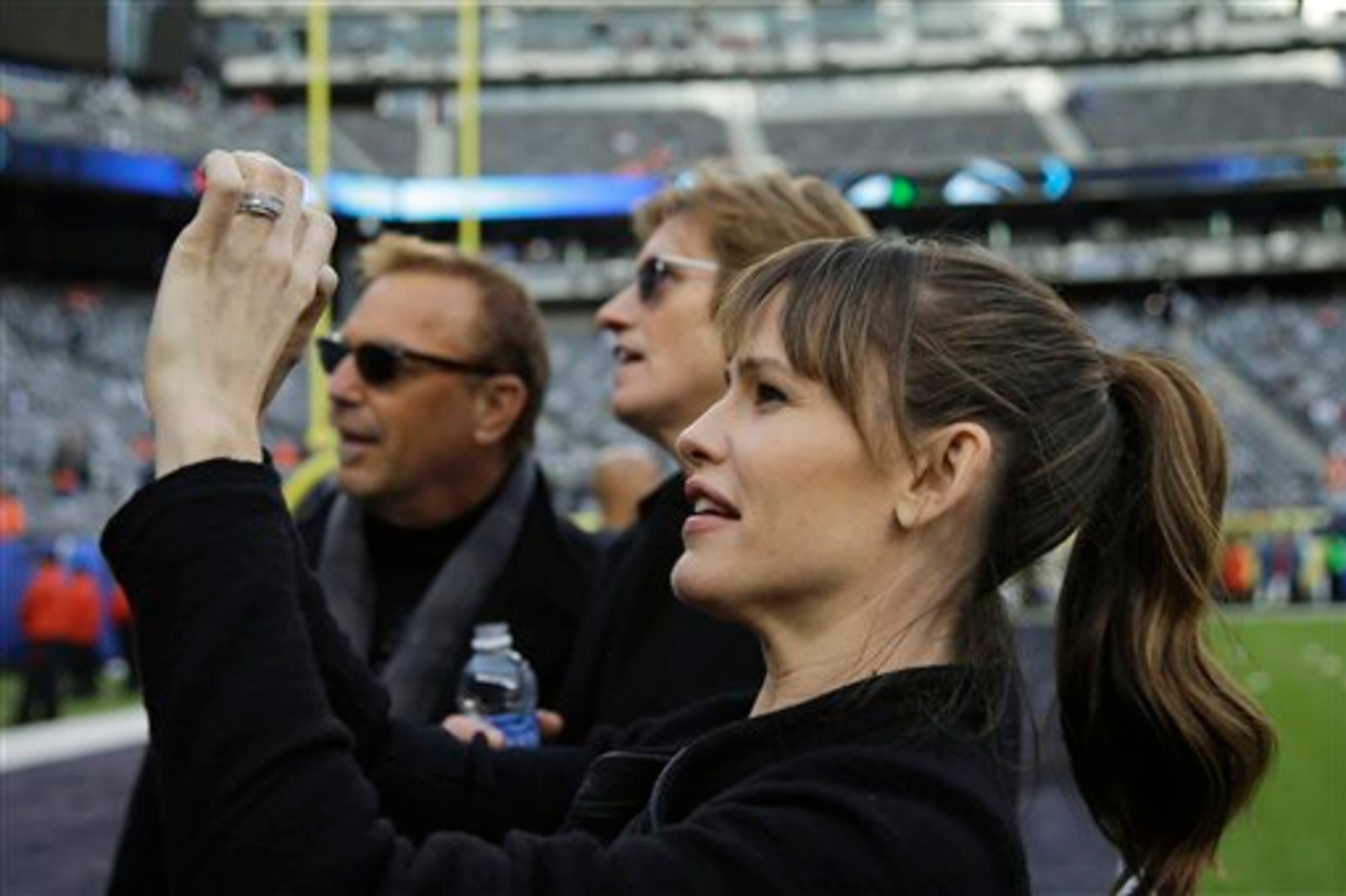 Actress Jennifer Garner takes a photo as actors Kevin Costner, left, and Denis Leary look on, at MetLife Stadium before the NFL Super Bowl XLVIII football game between the Seattle Seahawks and the Denver Broncos Sunday, Feb. 2, 2014, in East Rutherford, N.J. (AP Photo/Matt Slocum)