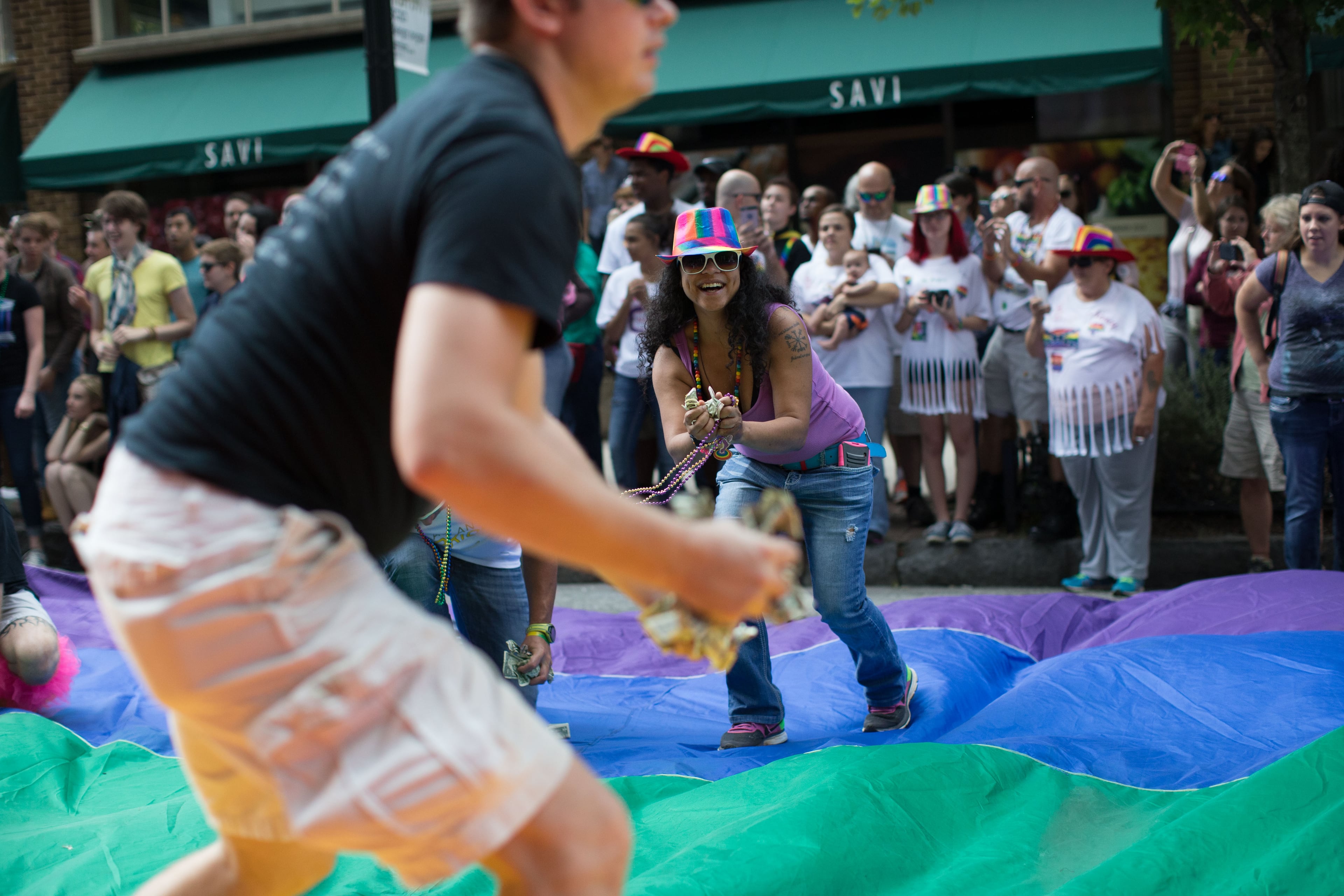 People help pick up money that was thrown on a large rainbow flag as donations during the Atlanta Pride Parade, Sunday, Oct. 11, 2015. BRANDEN CAMP/SPECIAL