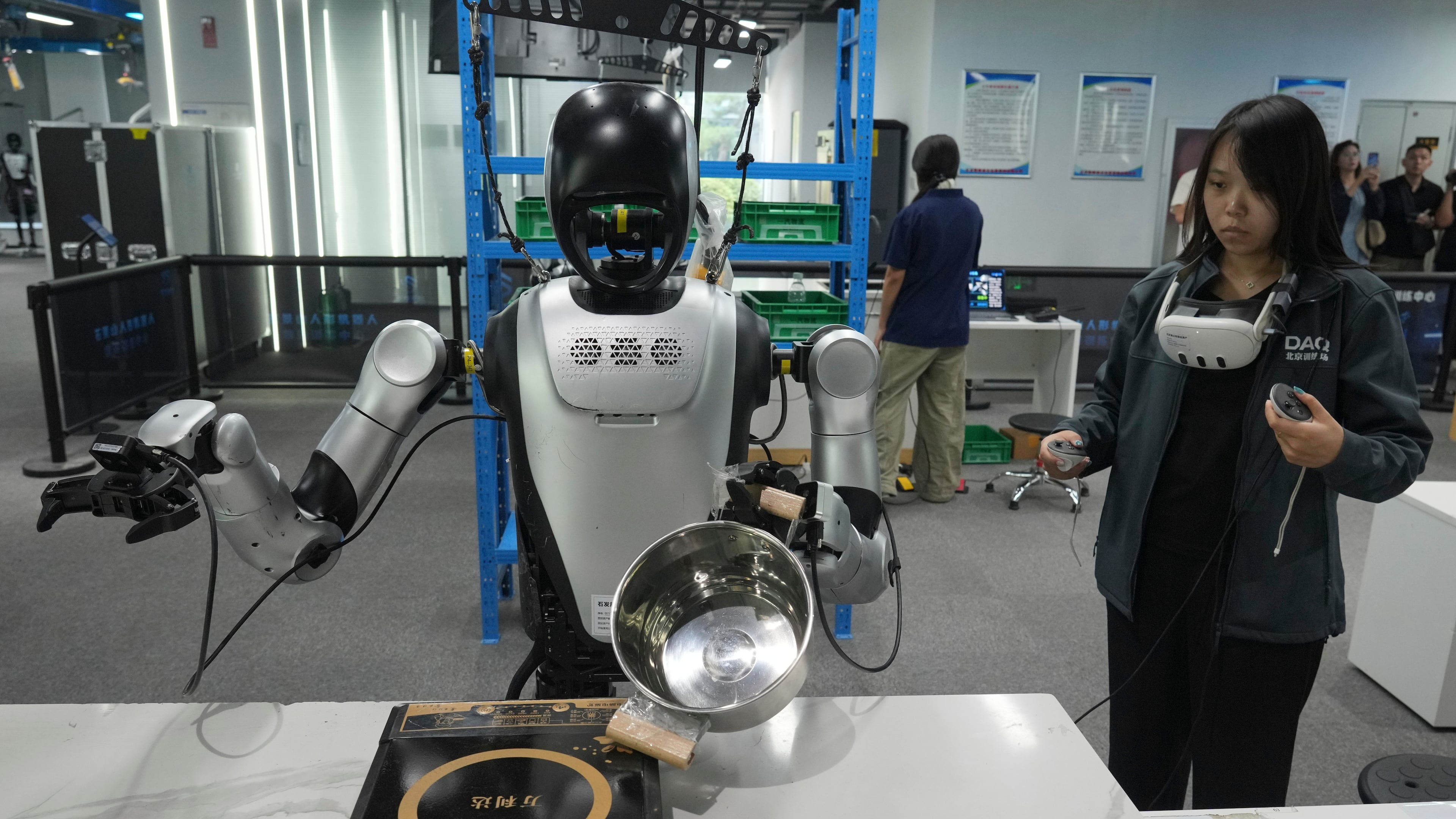 A worker remote controls humanoid robots during the one month countdown of 2026 China International Fair for Trade in Services (CIFTIS) at a robot training center in Beijing, China, Monday, Aug. 10, 2026. (AP Photo/Achmad Ibrahim)