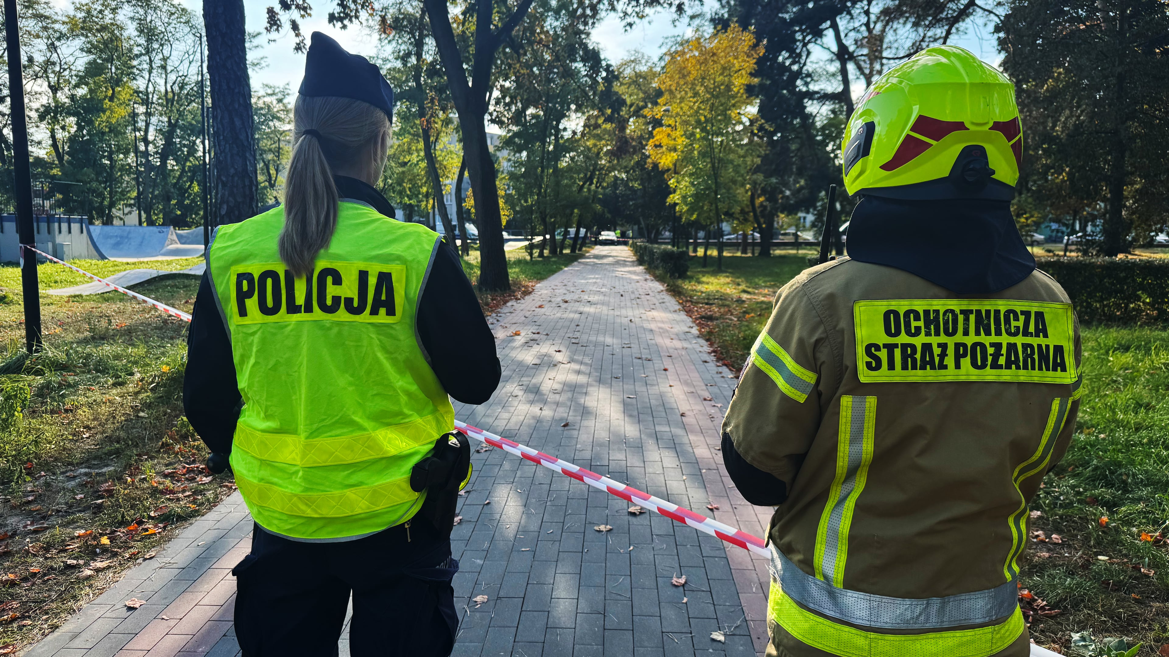 A police officer and a volunteer firefighter look down the street near a cordoned-off area following an attack on the Vocational School Complex No. 4 in Ostroleka, Poland, Wednesday, Oct. 7, 2026. (AP Photo/Rafal Niedzielski)
