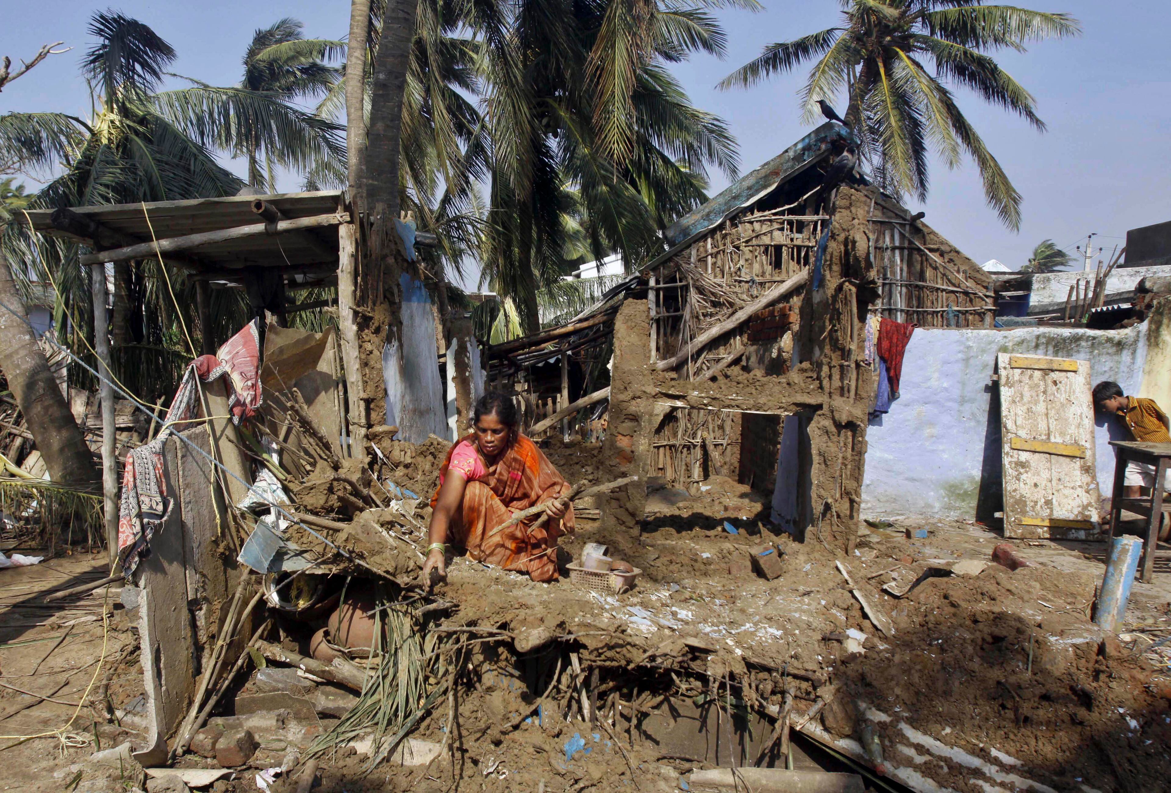 An Indian woman collects her belongings after returning to the cyclone-hit Haripur village on the Bay of Bengal coast in Ganjam district, Orissa state, India, Monday, Oct. 14, 2013. A mass government evacuation of nearly 1 million people spared India the widespread deaths many had feared from the powerful weekend cyclone, which destroyed hundreds of millions of dollars' worth of crops and tens of thousands of homes. (AP Photo/Biswaranjan Rout)