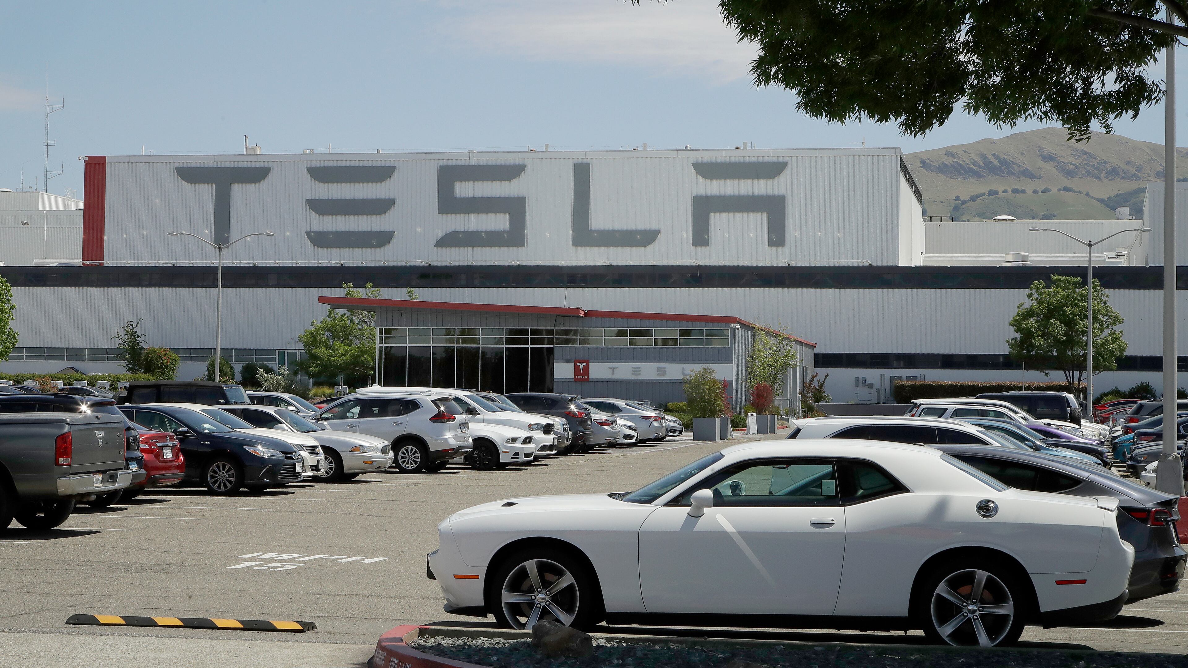 Vehicles are seen parked at the Tesla car plant Monday in Fremont, California. The parking lot was nearly full at Tesla’s California electric car factory, an indication the company could be resuming production in defiance of an order from county health authorities.