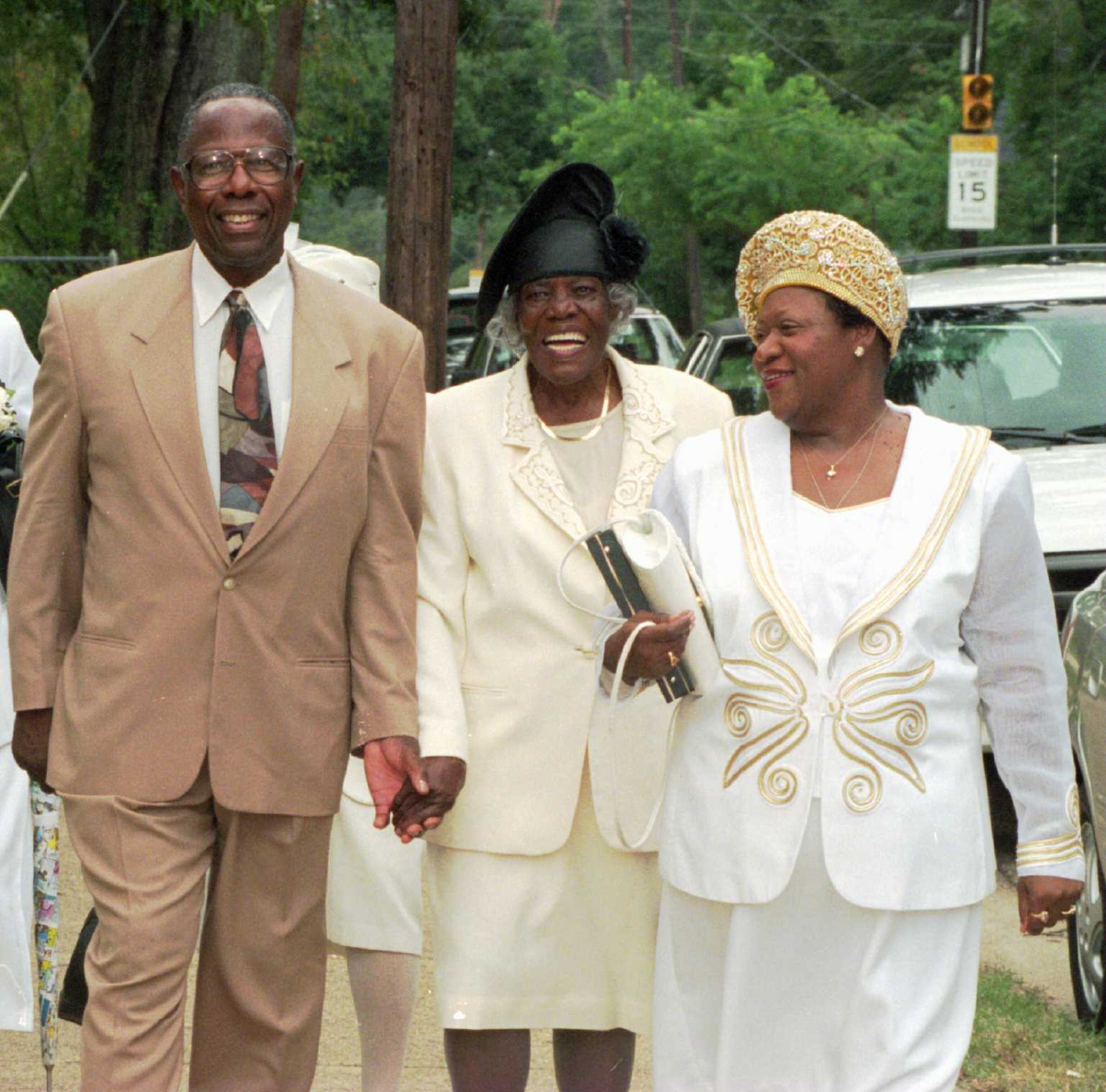 Baseball Hall of Famer Henry Aaron, left, back in his hometown, escorts his mother Estella Aaron, center, of Mobile, Ala. to the Greater Morning Star Baptist Church Sunday, Sept 15, 1996 in Mobile. Mrs. Aaron was named the Church's 1996 Woman of the Year. At right is Henry Aaron's niece, Joyce Brown of Birmingham, Ala. (AP Photo/Mobile Register, G.M. Andrews)