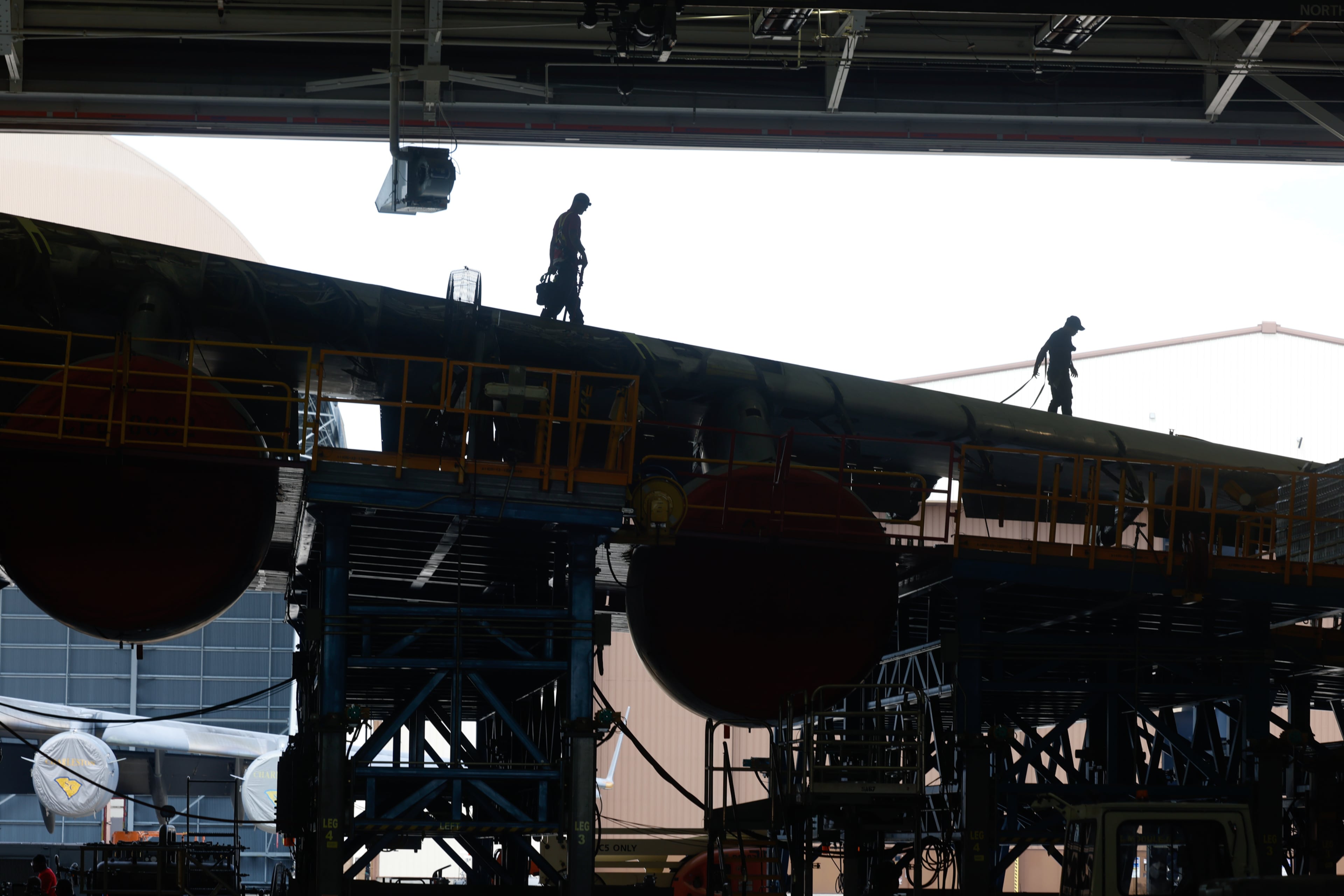 Workers walk on the wing of a C-5 aircraft under repair at a hangar in Robins Air Force Base in Houston County on Friday, Aug. 21, 2026. (Arvin Temkar/AJC)