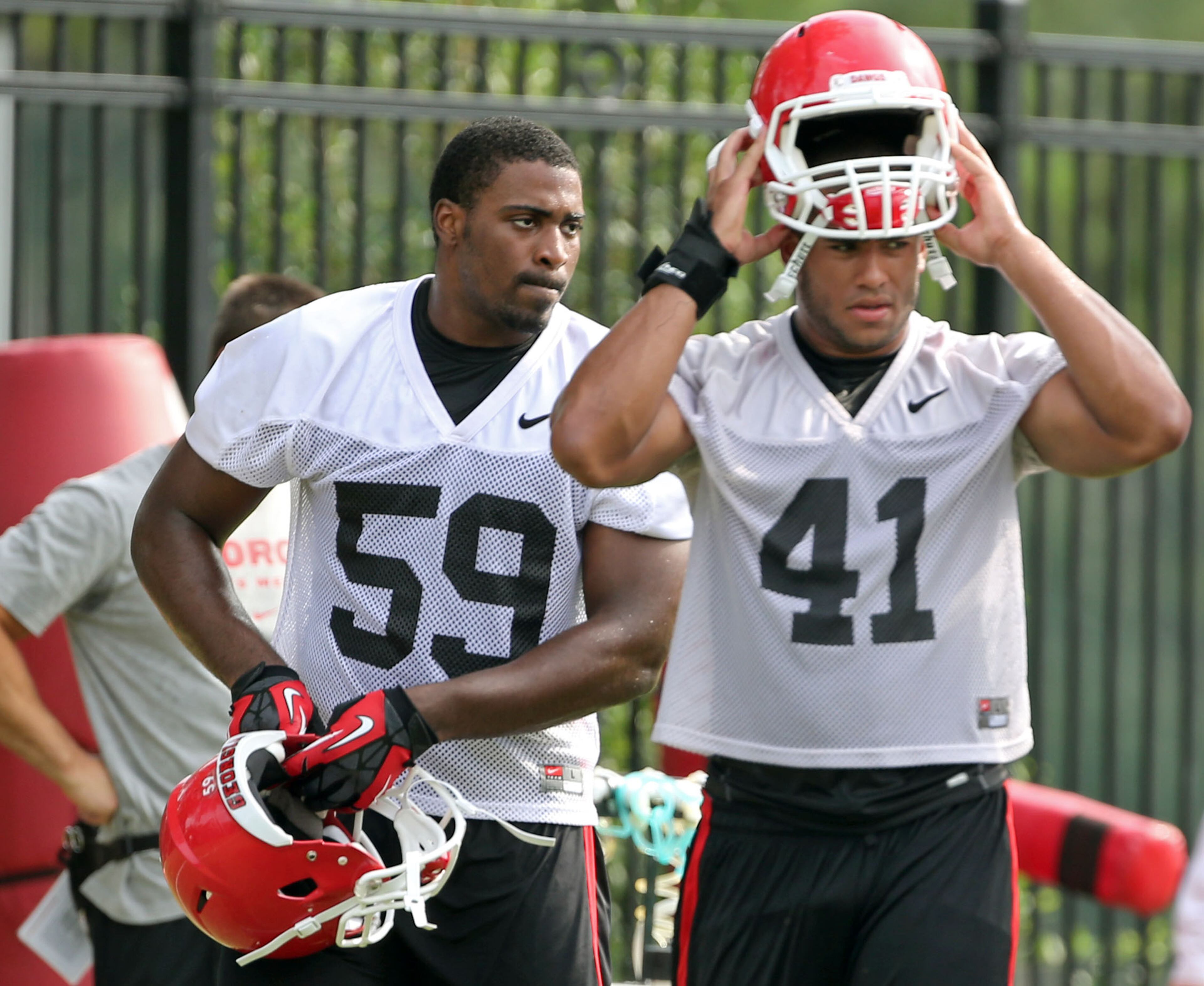 University of Georgia outside linebackers Jordan Jenkins (59) and Brandon Burrows (41) put on their helmets and prepare for another drill following a water break during preseason practice at the University of Georgia Tuesday afternoon in Athens, Ga., August 6, 2013. JASON GETZ / JGETZ@AJC.COM