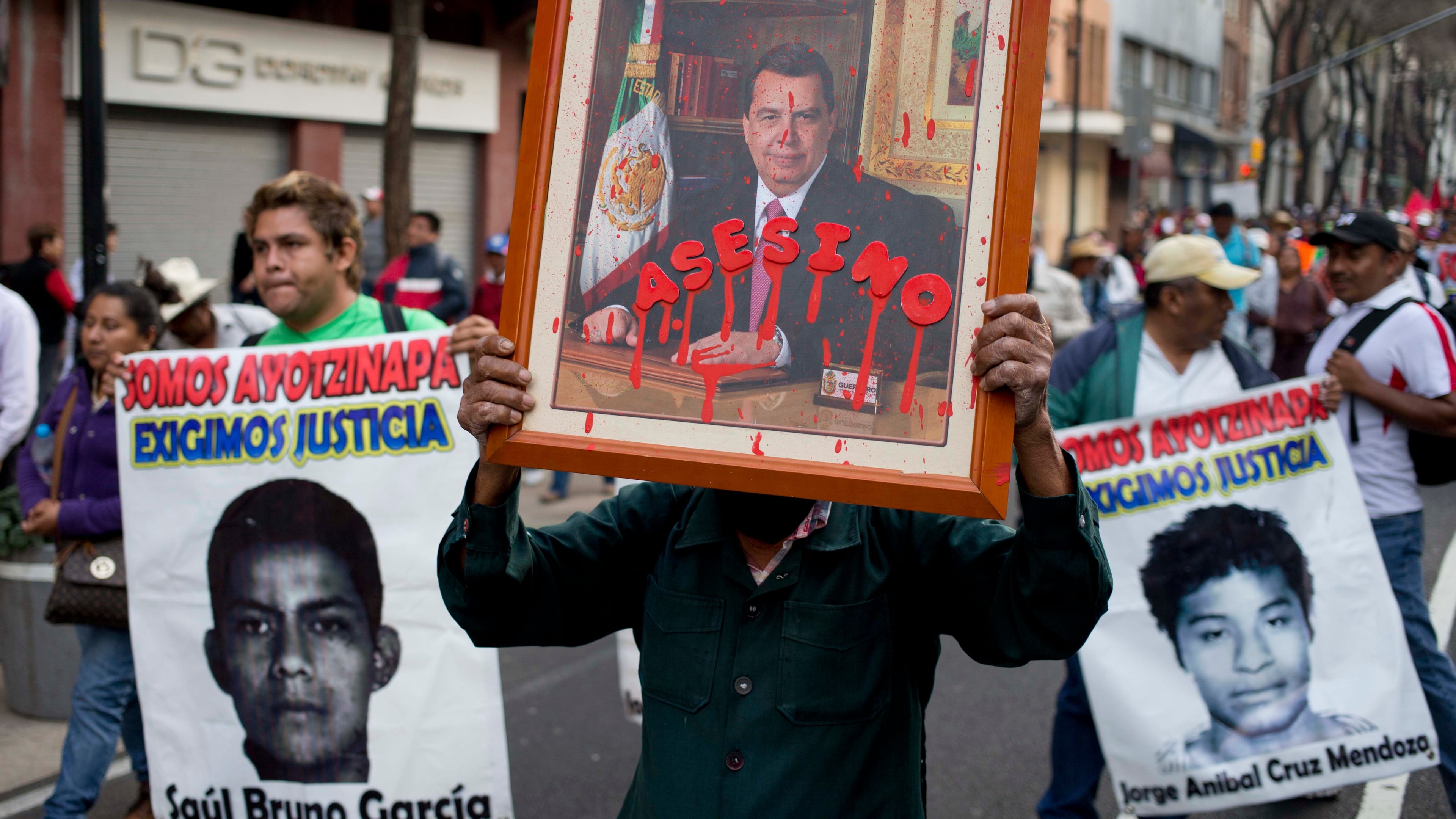 FILE - A protestor holds a portrait of Angel Aguirre, the former governor of Guerrero state, with the Spanish word for assassin written across it, during a march against the disappearance of 43 students from a rural teachers' college, Jan. 26, 2015, in Mexico City. (AP Photo/Eduardo Verdugo, File)