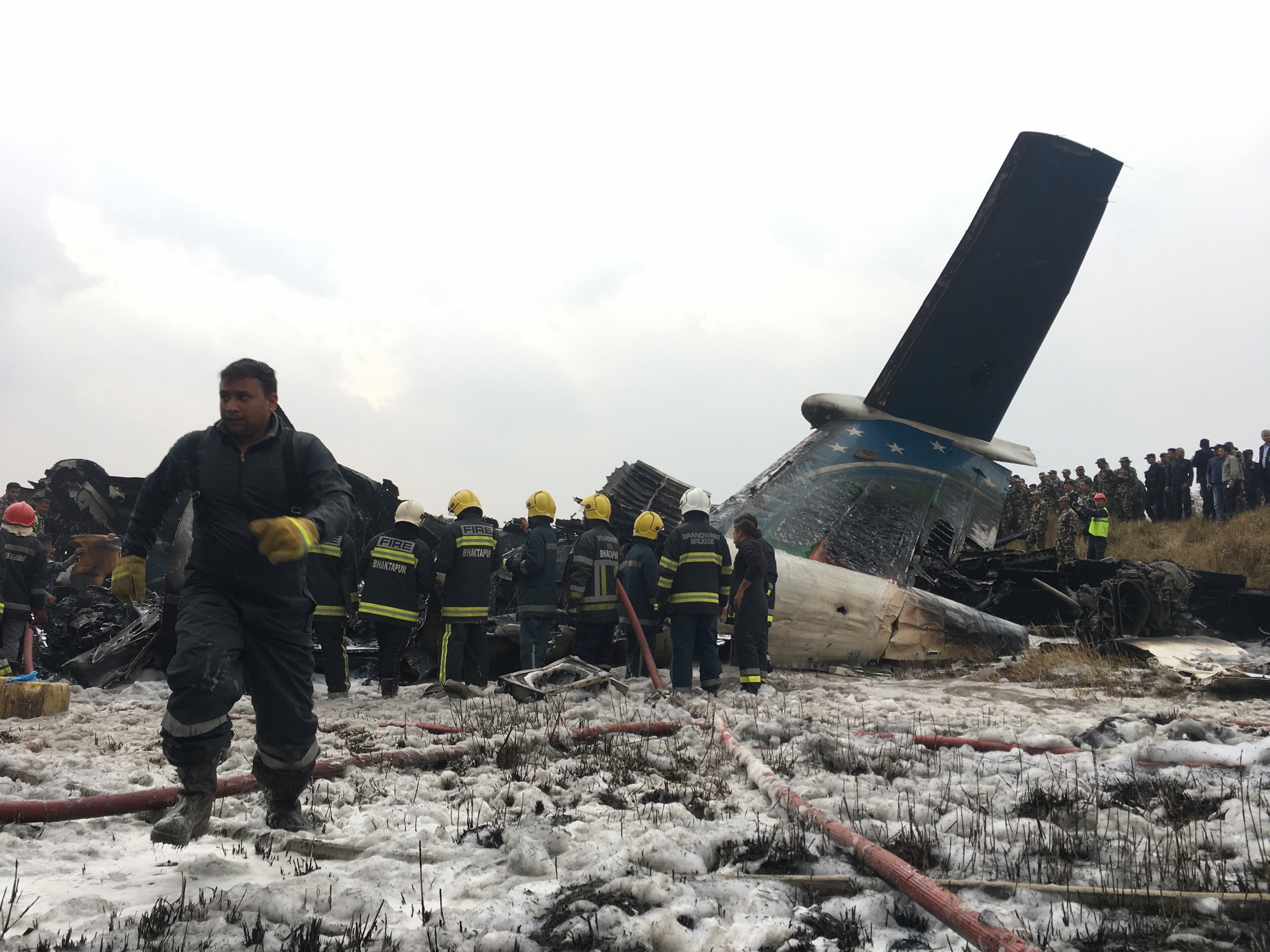 Nepalese rescuers stand near a passenger plane from Bangladesh that crashed at the airport in Kathmandu, Nepal, Monday, March 12, 2018. (AP Photo/Niranjan Shreshta)