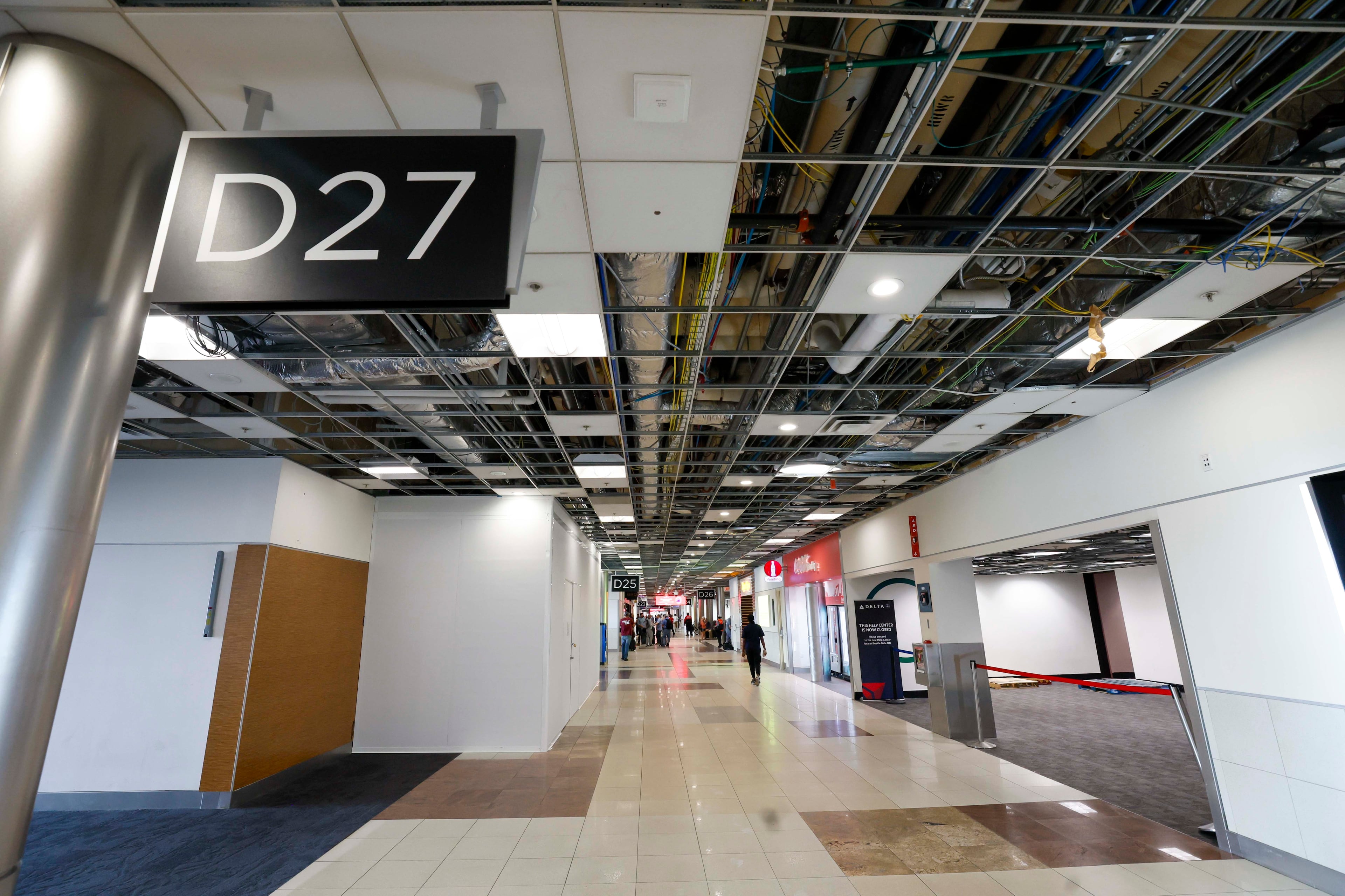 A section of Concourse D shows parts of the ceiling open with visible wires, as people continue to use the concourse while it is being expanded. The complete expansion is scheduled to be finished during the summer of 2029. (Miguel Martinez/AJC)