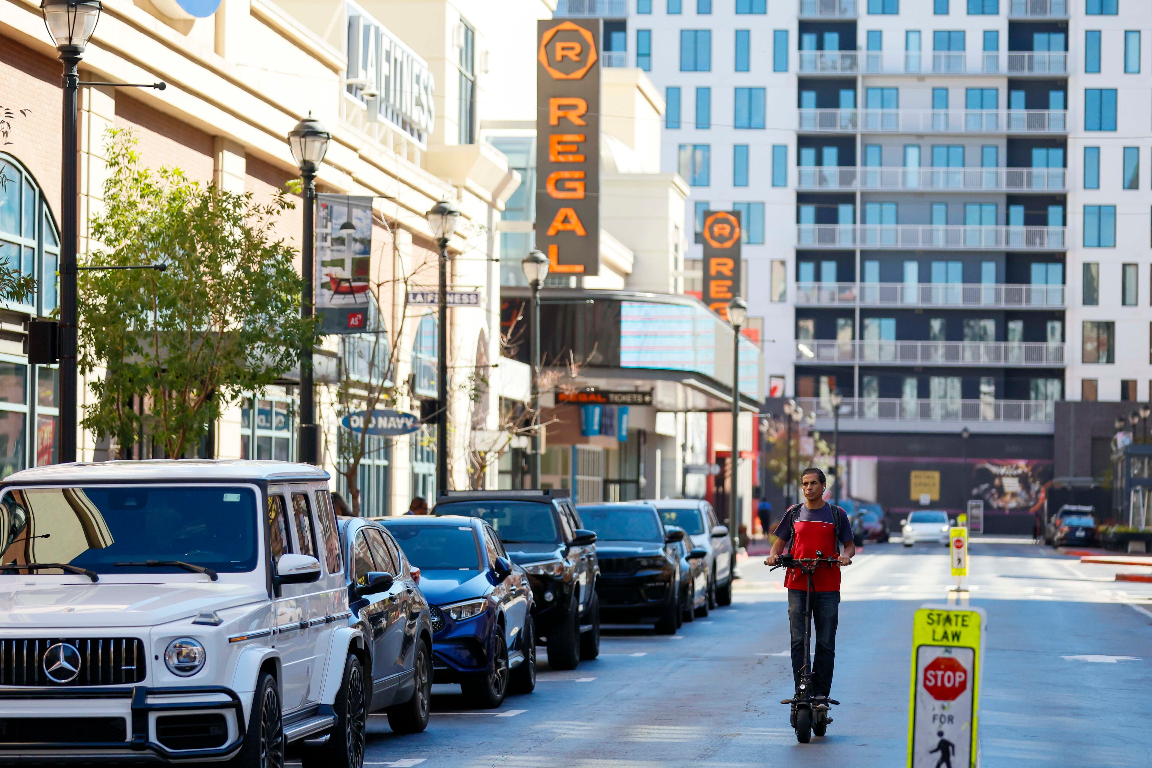 A person rides a scooter past the Regal Cinemas sign at Atlantic Station in the main square on Thursday, Oct. 16, 2025. (Miguel Martinez/AJC)