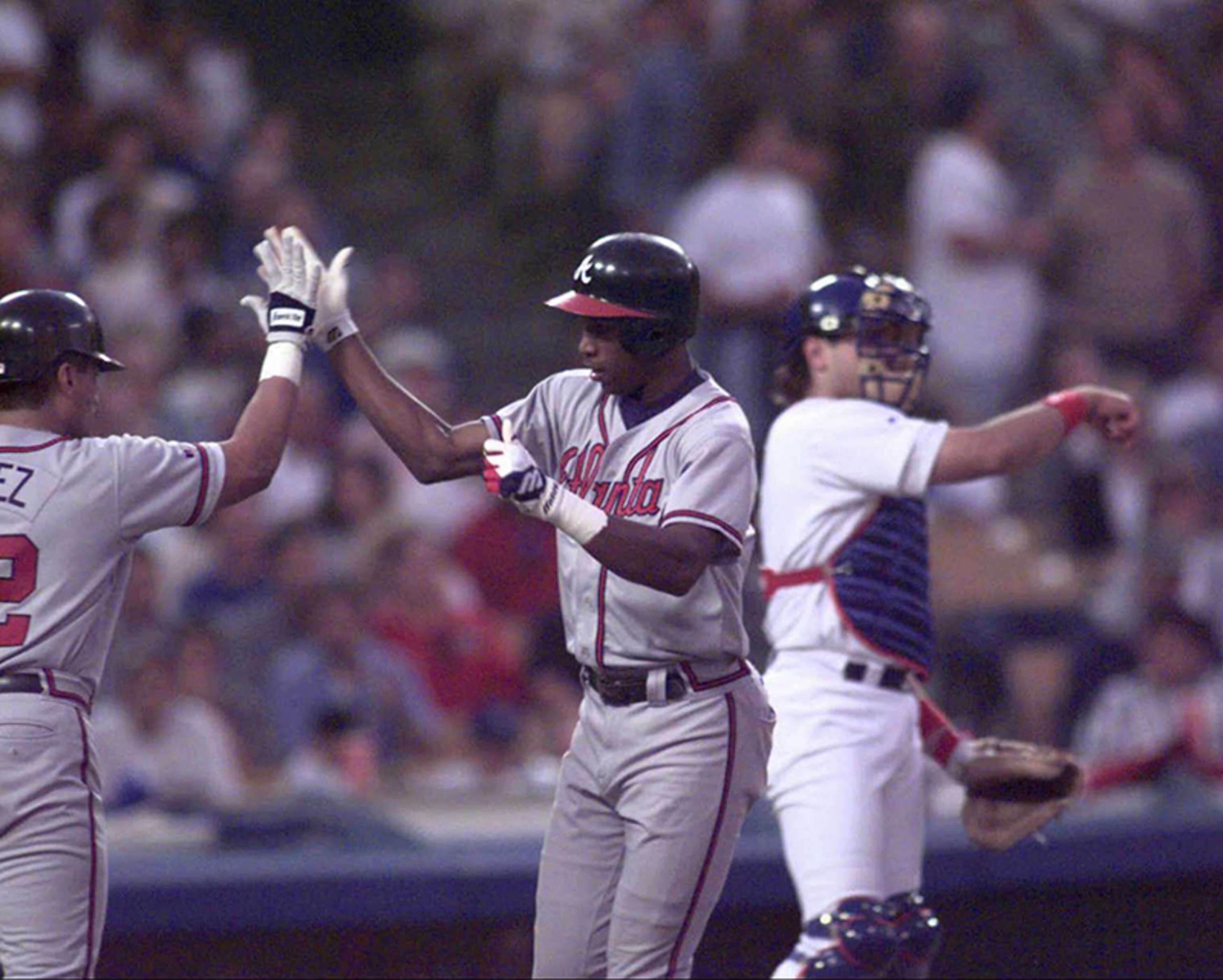 Atlanta Braves outfielder Jermaine Dye gets a high-five from Eddie Perez after Dye's 7th-inning homer put Braves up 3-2. Dye's in Game 2 of the National League Division Series against the Los Angeles Dodgers. The run held up as the Braves went on to win by that score.