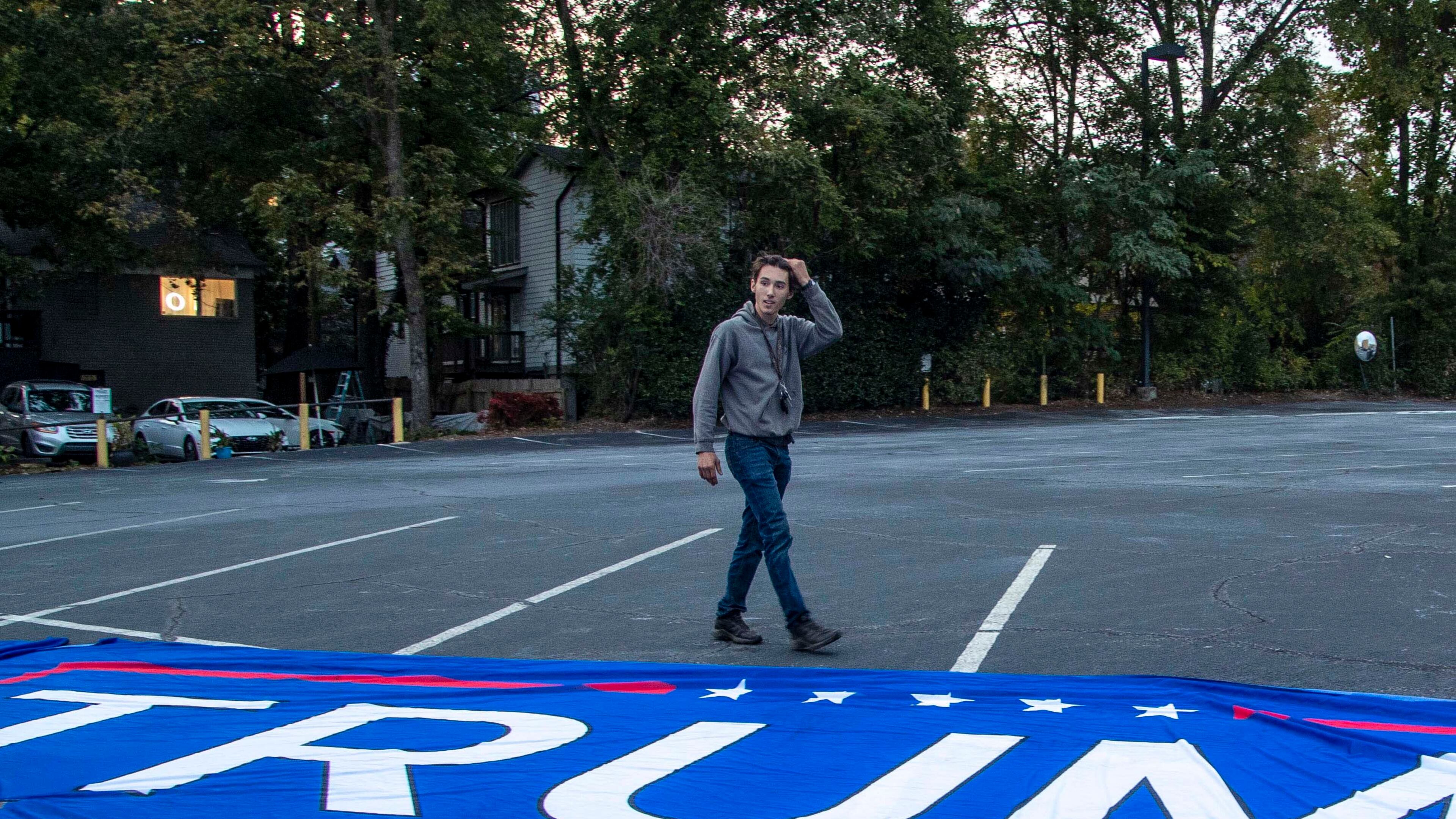 Bruno Cua unfurls a large Trump flag during a rally in the parking lot at the Georgia Republican Party headquarters in Buckhead on Thursday, November 5, 2020, two months before he was alleged to have stormed the U.S. Capitol and assaulted a federal officer. (Alyssa Pointer / Alyssa.Pointer@ajc.com)