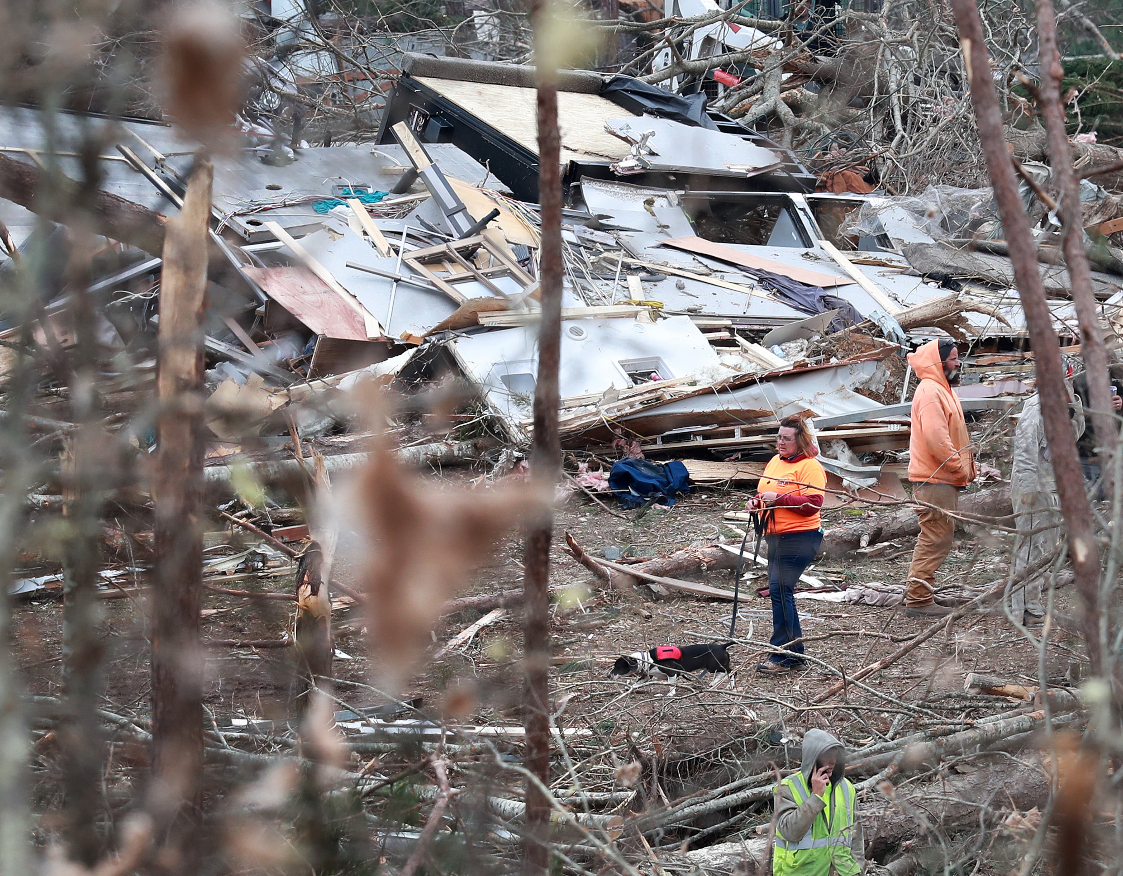 A woman and her dog make their way through the remains of shattered homes as rescue workers, local residents, and volunteers work through the debris along Lee Road 38 after a F-3 tornado on Monday, March 4, 2019, in Beauregard. Twenty-three people -- including a six-year-old -- were killed by a storm Sunday, though that number is expected to climb, Lee County Sheriff Jay Jones told reporters Monday morning. The destruction area is at least a half a mile wide and at least a mile long, he added. Curtis Compton/ccompton@ajc.com