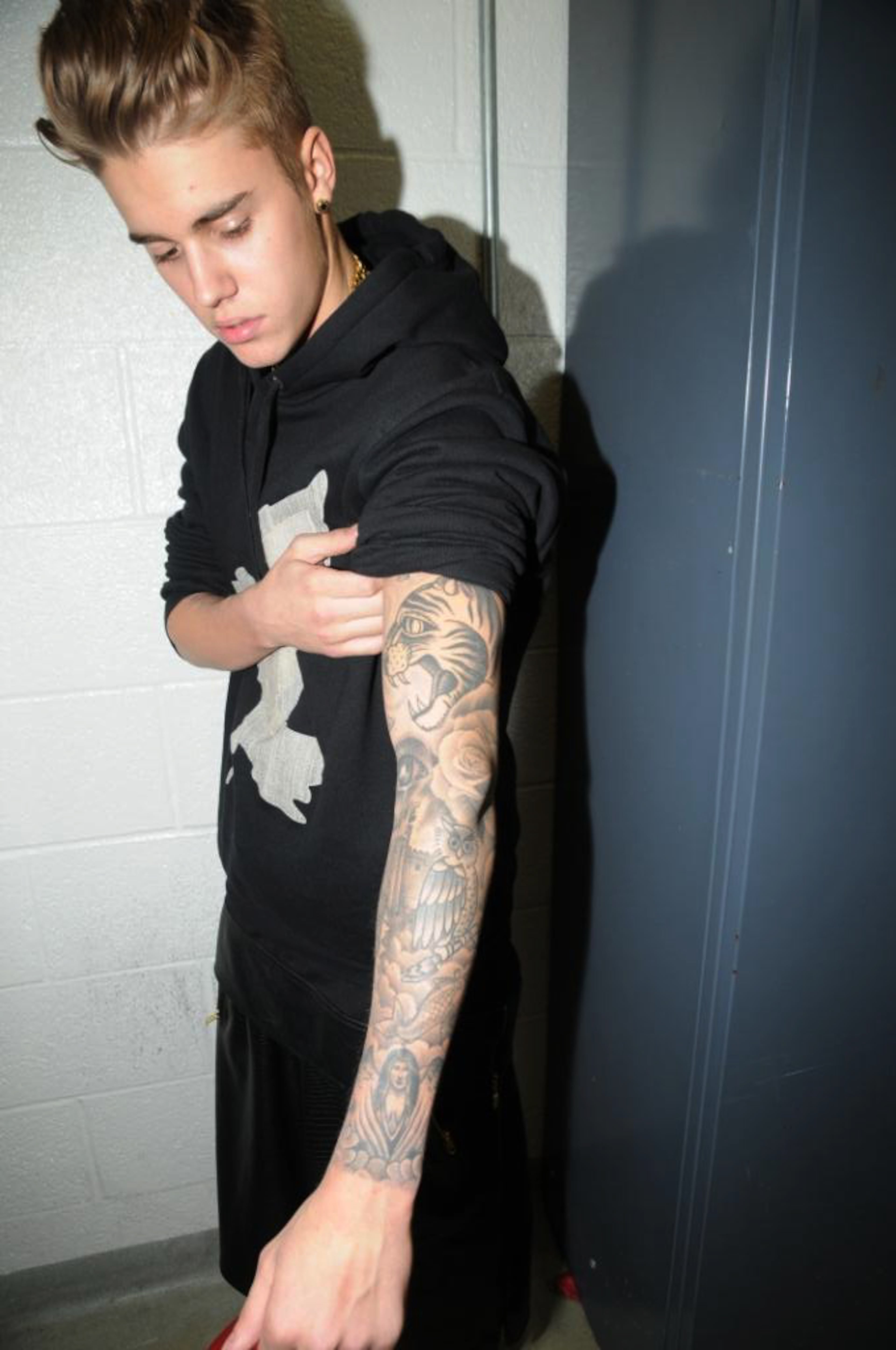 In this Jan. 23, 2014 photo made available by the Miami Beach Police Dept. on Tuesday, March 4, 2014, Justin Bieber shows his tattoos at the police station after his arrest in Miami Beach, Fla. Bieber has pleaded not guilty to charges of driving under the influence, resisting arrest and driving with an expired license. He and R&B singer Khalil Amir Sharieff were arrested early on Jan. 23 during what police called an illegal street drag race between a Lamborghini and a Ferrari. Neither has been charged with drag racing.