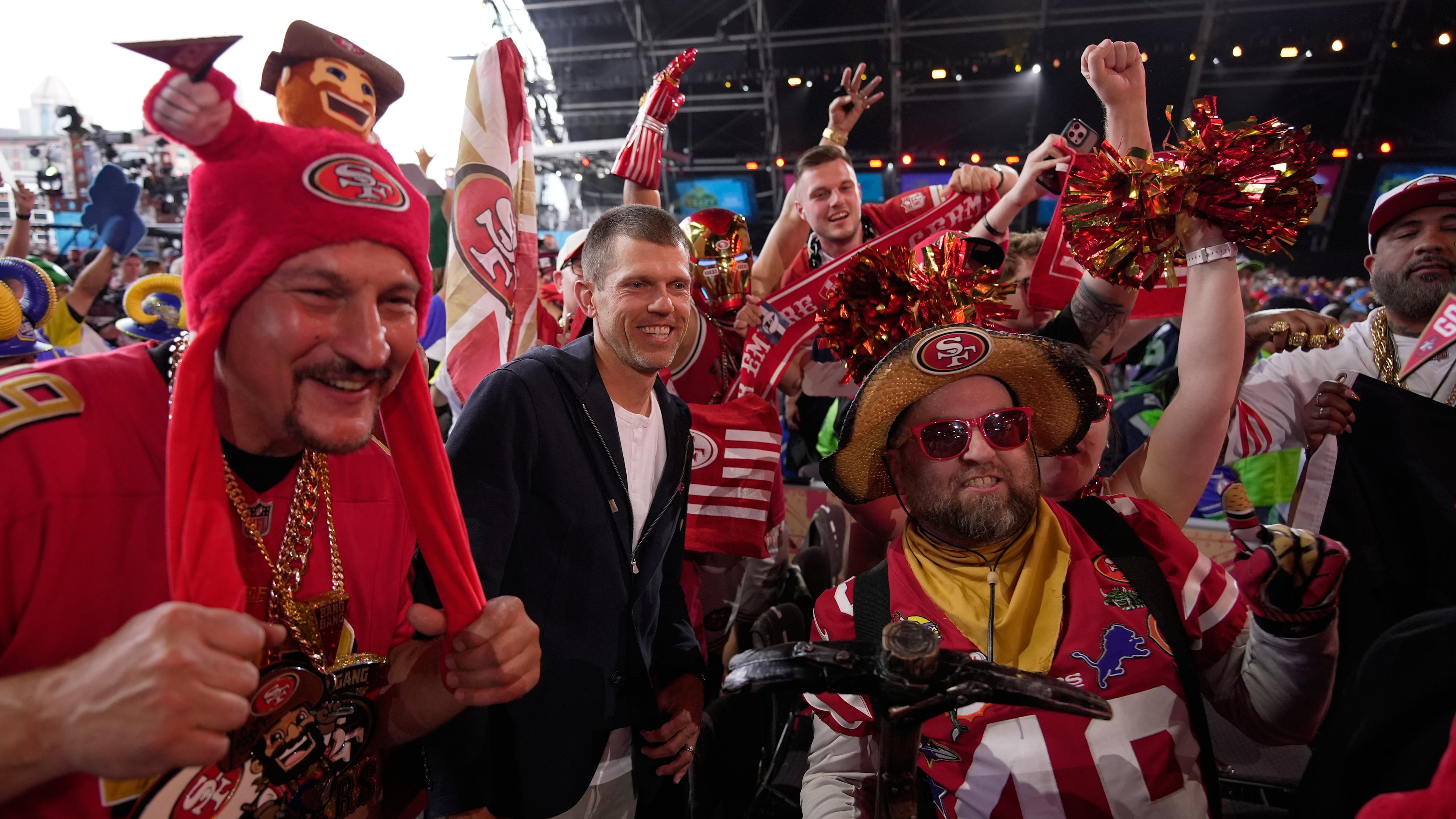 Former NFL player Andy Lee, center, poses with San Francisco 49ers fans during the second round of the NFL football draft, Friday, April 24, 2026, in Pittsburgh. (AP Photo/Sue Ogrocki)