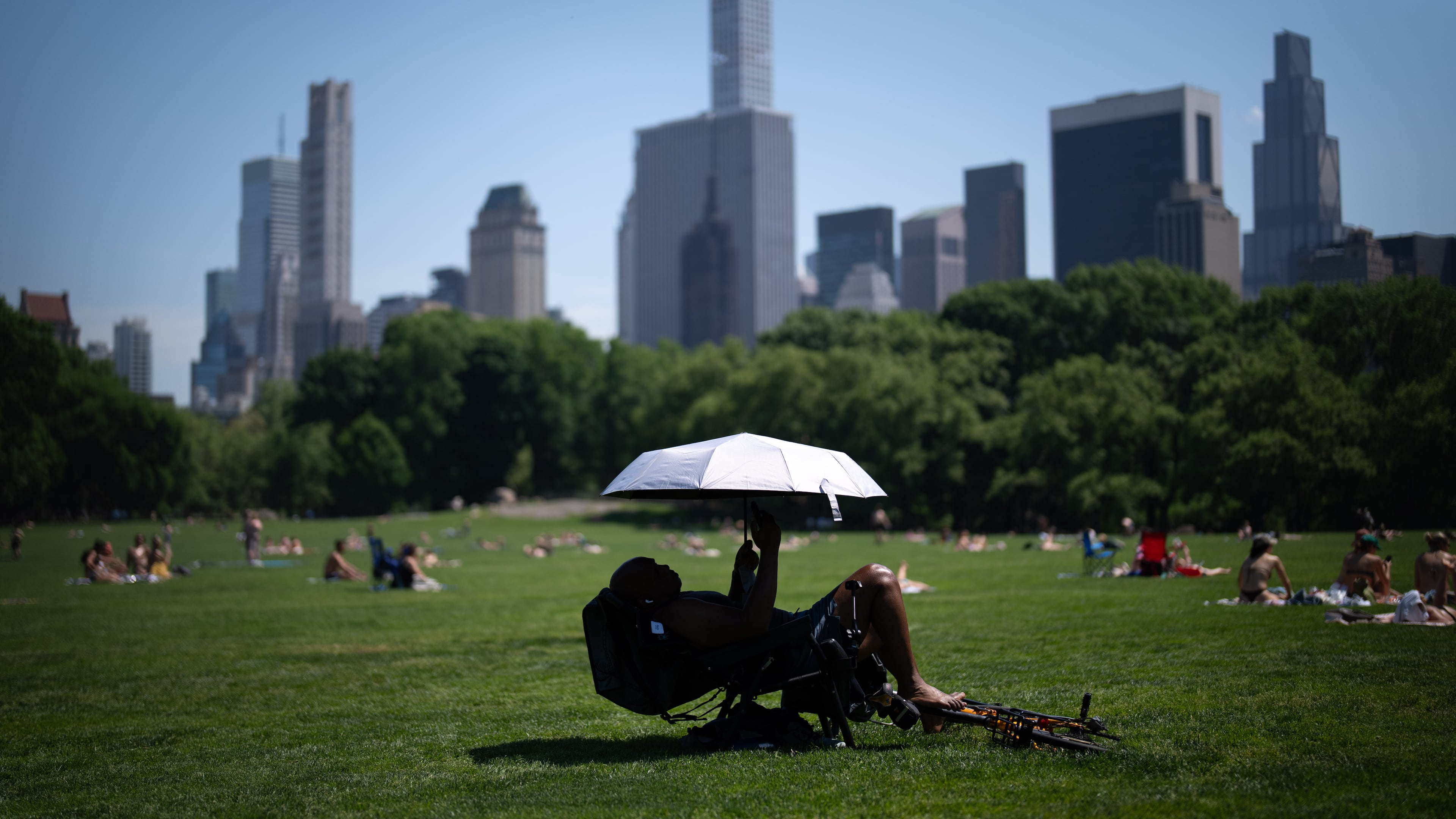 A person uses an umbrella to shield themselves from the sun during a heat advisory in Central Park, Tuesday, May 19, 2026, in New York. (AP Photo/Adam Gray)