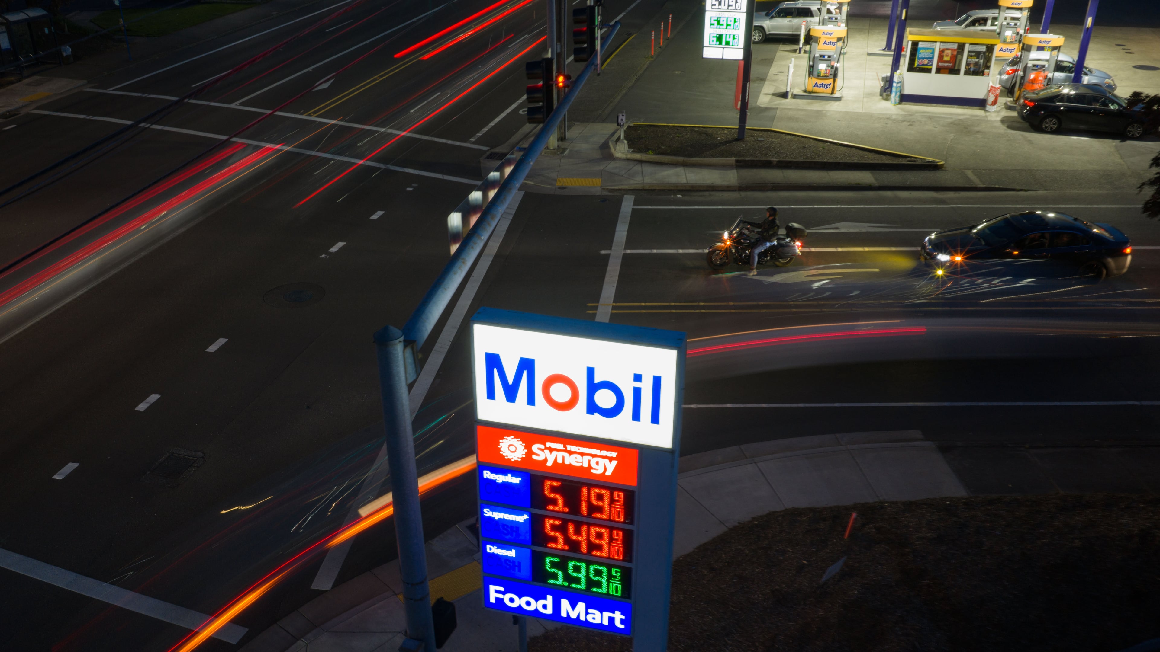 In this photo taken with a slow shutter speed, traffic moves past a sign for a Mobil gas station on Wednesday, April 29, 2026, in Portland, Ore. (AP Photo/Jenny Kane)