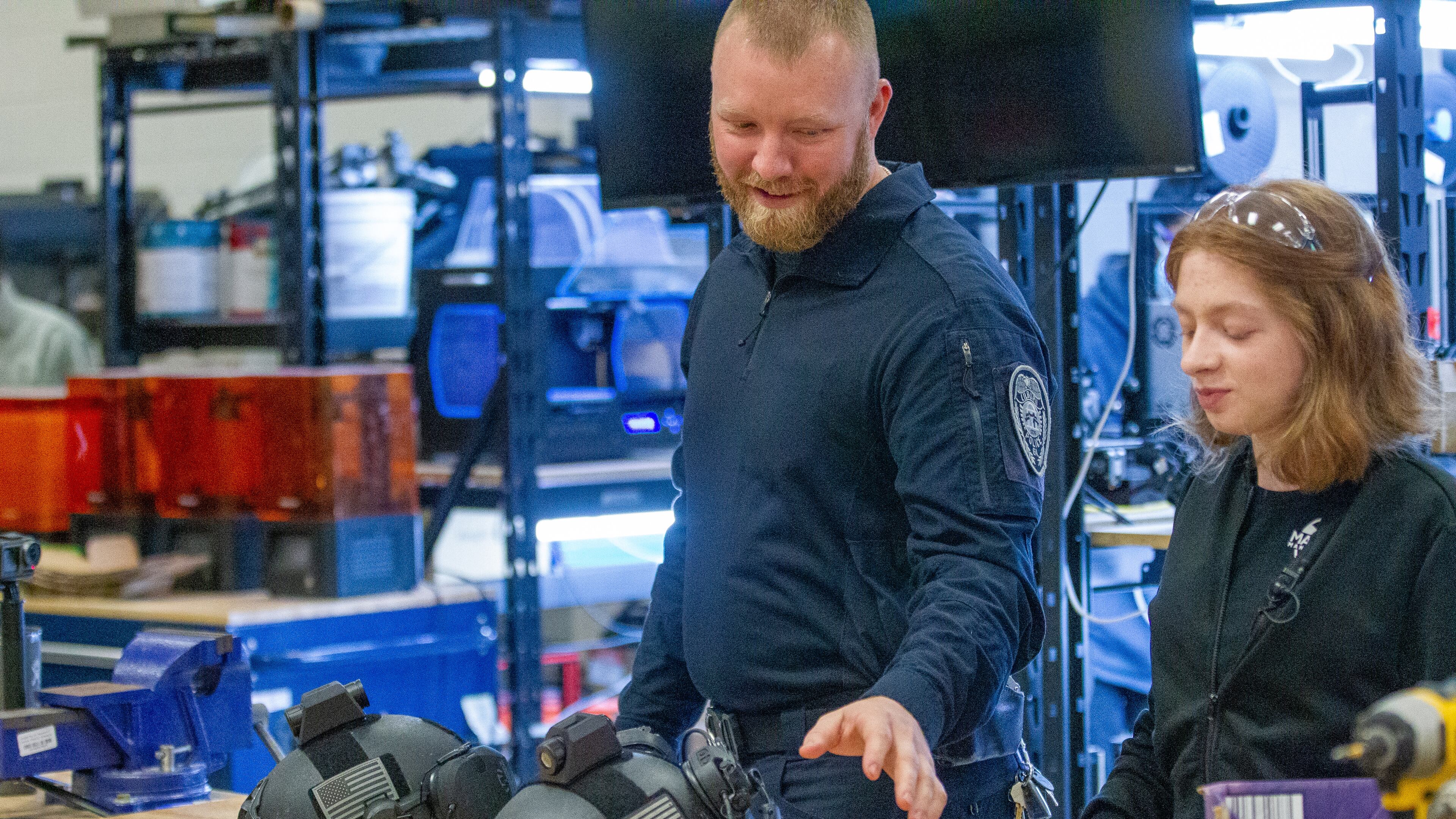 Cody Belcher, an investigator for the Lilburn Police Department, and Sarah Andrews, a senior at Maxwell High School of Technology, talk about the camera mount that Andrews designed for a team of local police officers Thursday, March 17, 2022. (Steve Schaefer for The Atlanta Journal-Constitution)