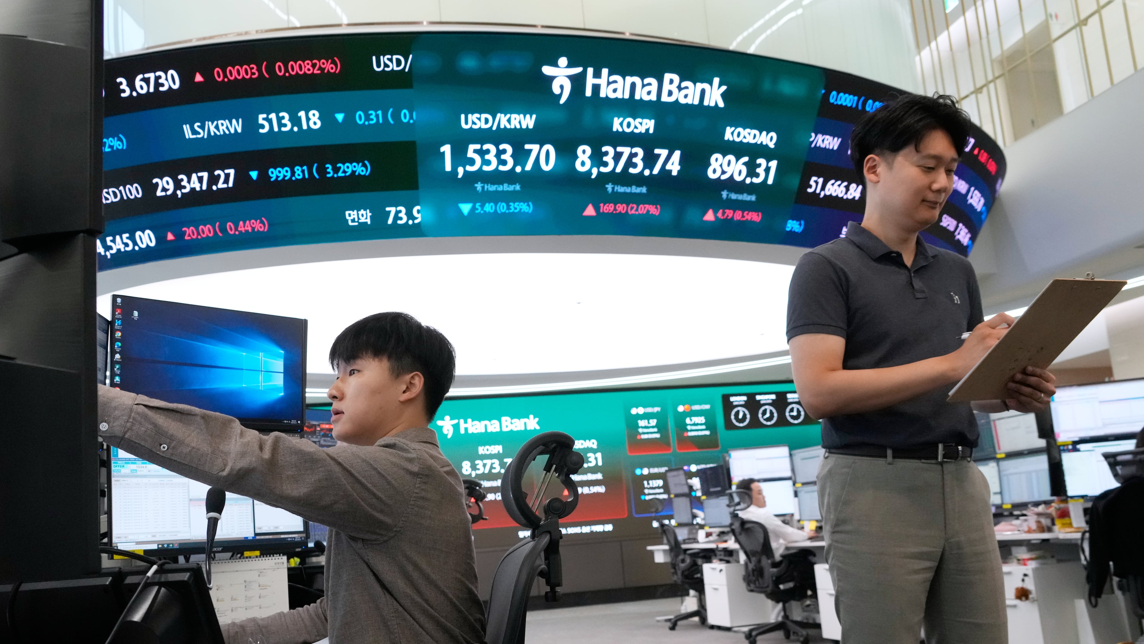 Currency traders work near a screen showing the Korea Composite Stock Price Index (KOSPI) and the foreign exchange rate between U.S. dollar and South Korean won at the foreign exchange dealing room of the Hana Bank headquarters in Seoul, South Korea, Wednesday, June 24, 2026. (AP Photo/Ahn Young-joon)