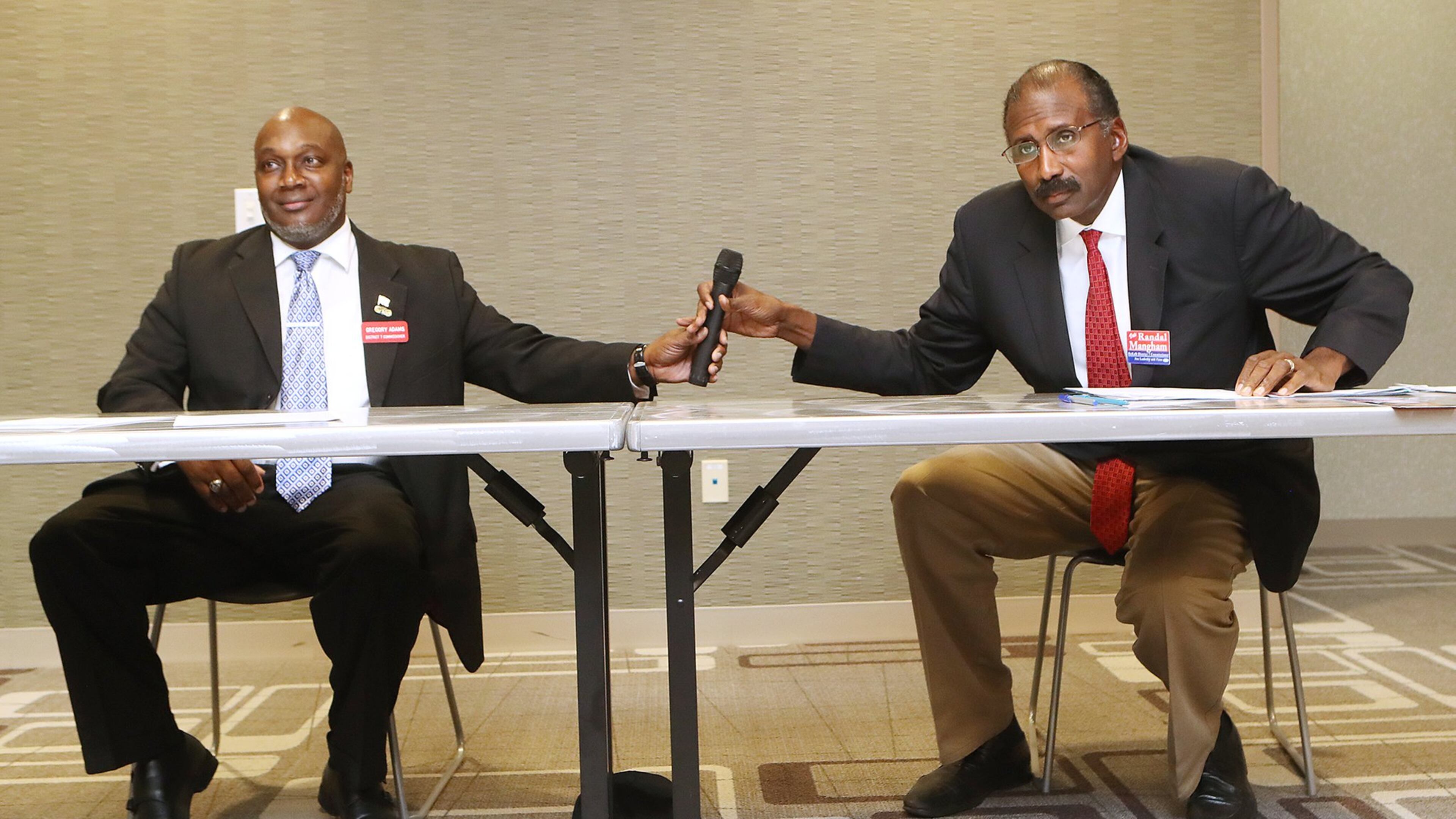 Candidates for the DeKalb County Commission Greg Adams, left, and Randal Mangham share a microphone while answering questions on how best to move the county forward during a debate at the Tucker-Reid H. Cofer Library on Nov. 29. Curtis Compton/ccompton@ajc.com