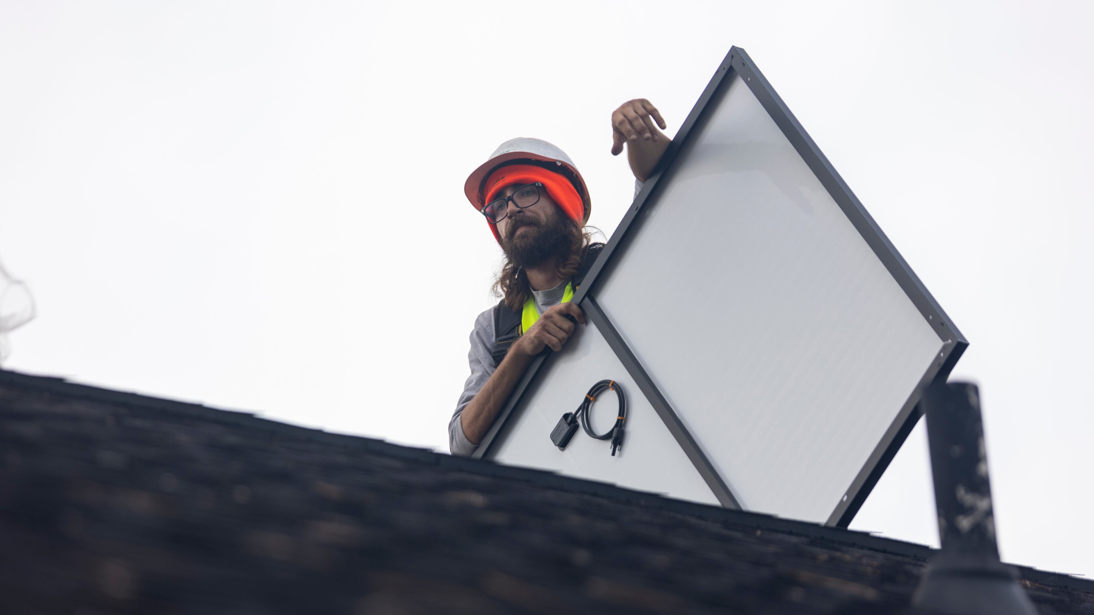 FILE: Joe McClain, an installer for Creative Solar USA, moves solar panels onto the roof of a home in Ball Ground, Georgia on Dec. 17th, 2021. (Nathan Posner for The Atlanta Journal-Constitution)